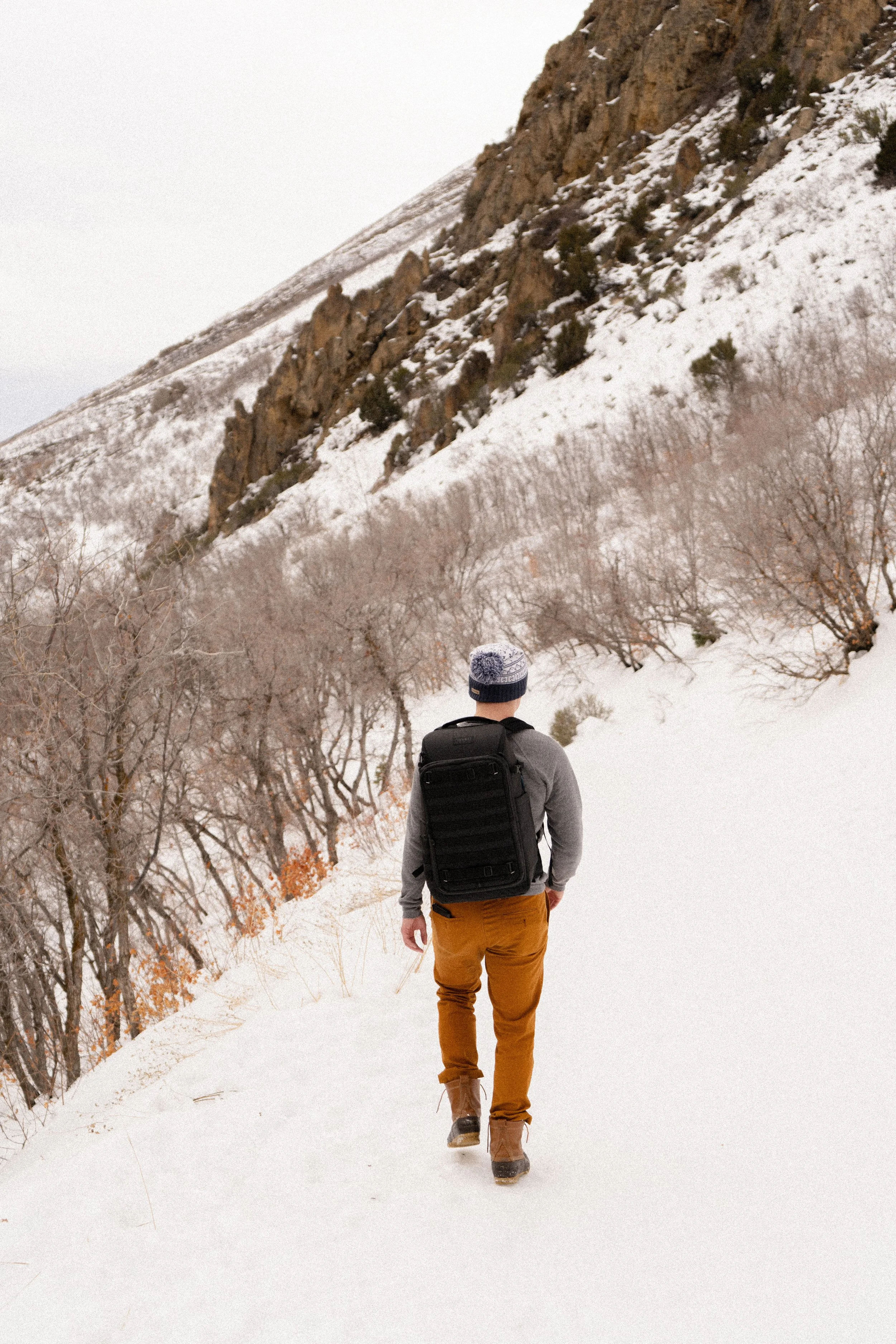 Hiker wearing winter gear on a snowy mountain trail