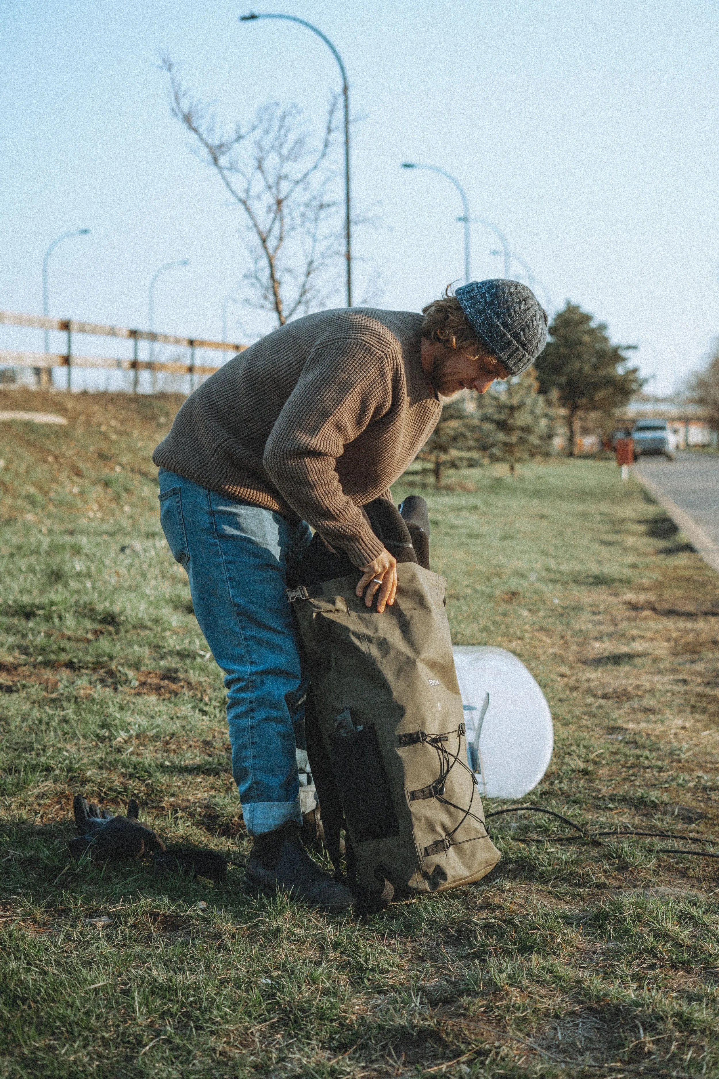 Person wearing a grey knit beanie packing a backpack outdoors