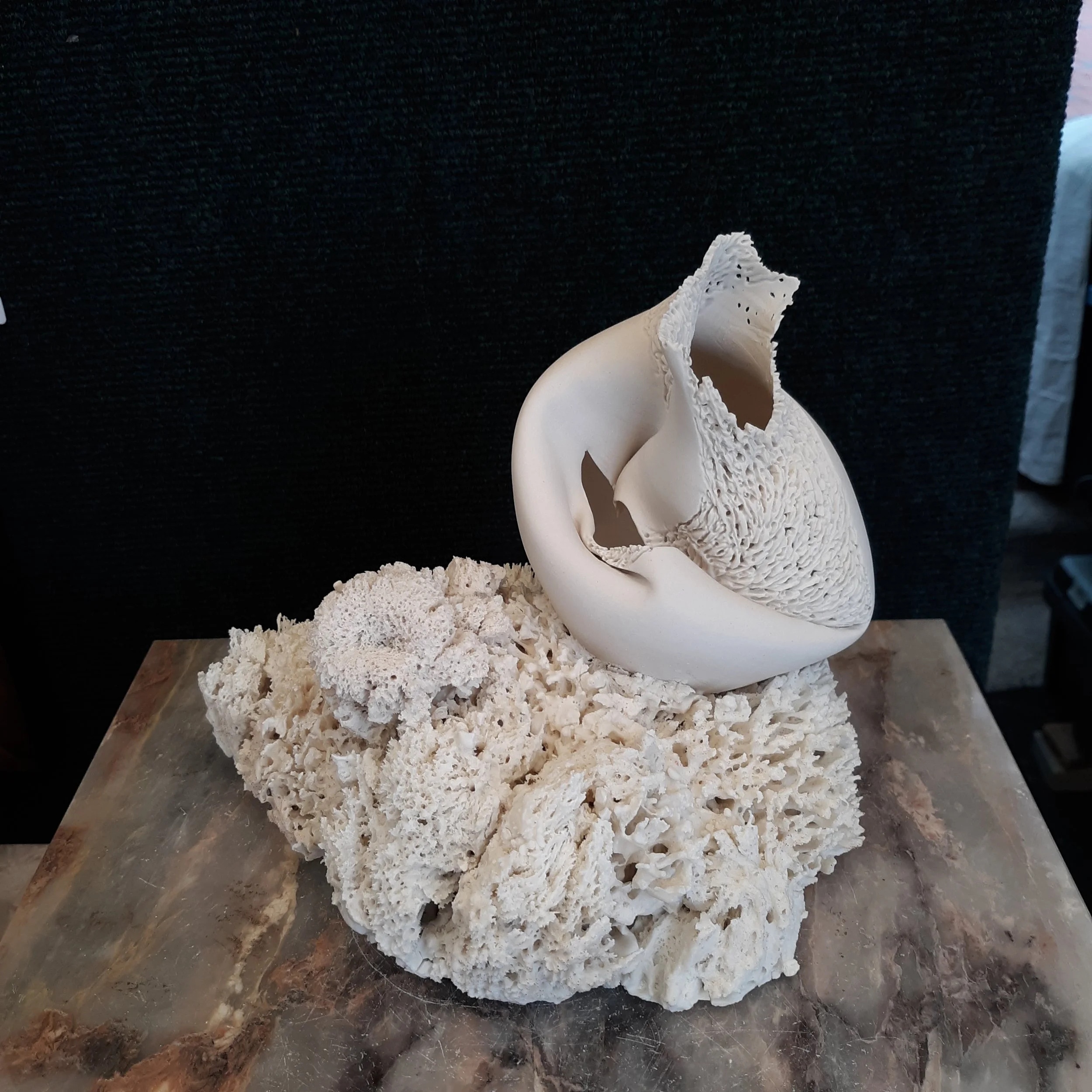 A sculpture of handmade porcelain coral with a porcelain vase, altered and carved fused to the porcelain coral base.