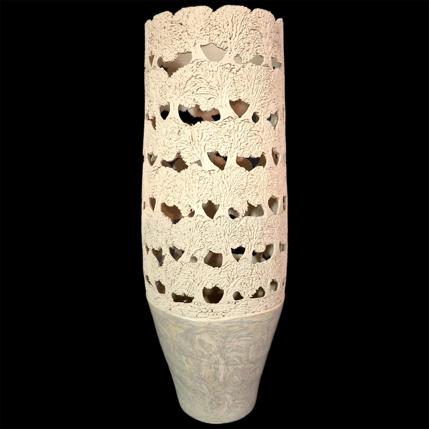Ceramic vase with intricate, layered tree pattern cut-outs, standing against a black background.