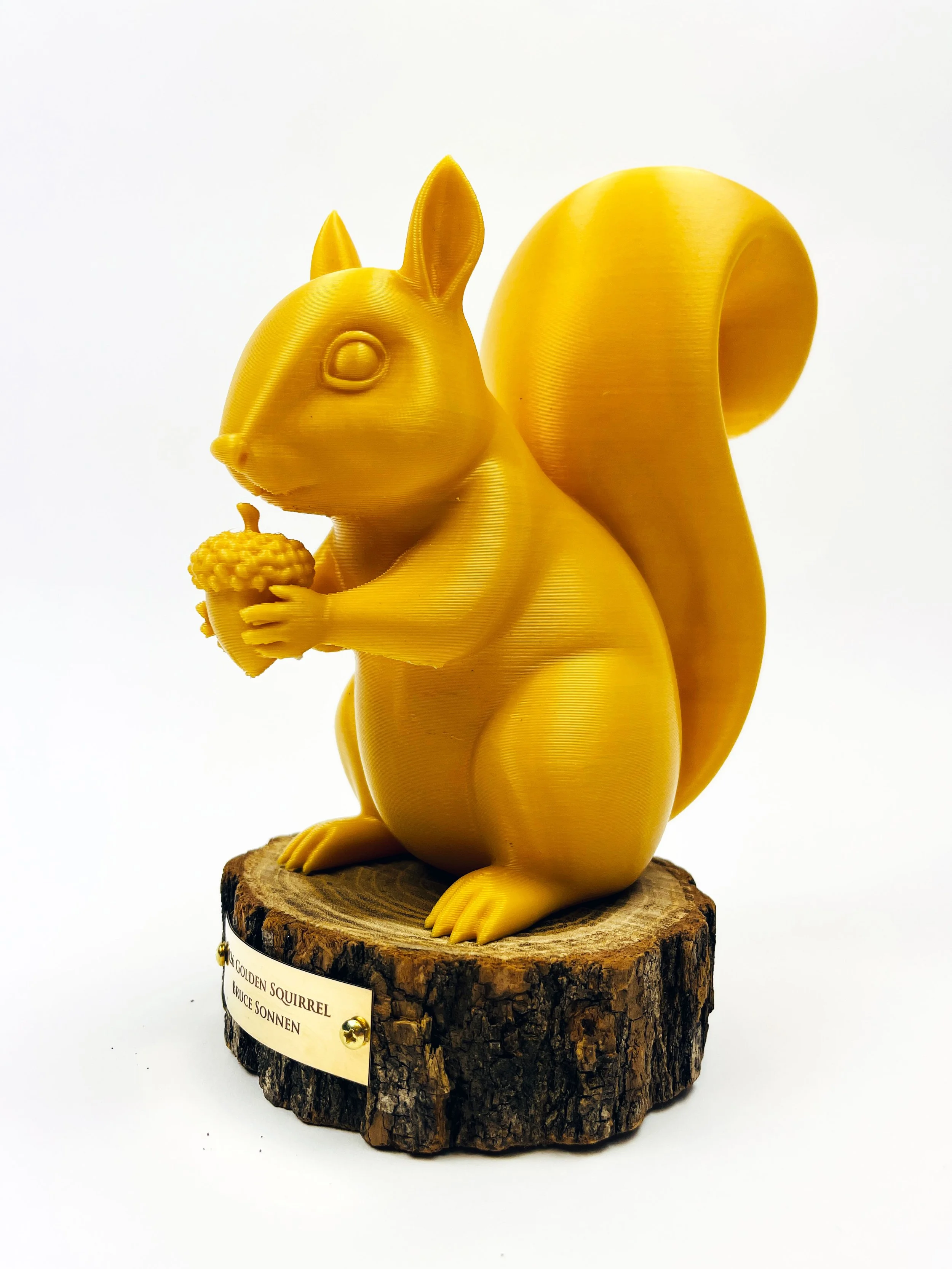 Customs Award with 3D printed yellow squirrel sculpture trophy holding acorns, on a round wood base with custom plaque. custom laser cutting and engraving, and fabrication by MC Laser Labs.