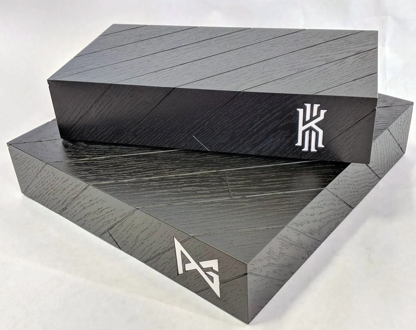 A black wooden box with a pyramid-shaped lid and white lever marks, sitting on a matching black wooden base, with a white background.