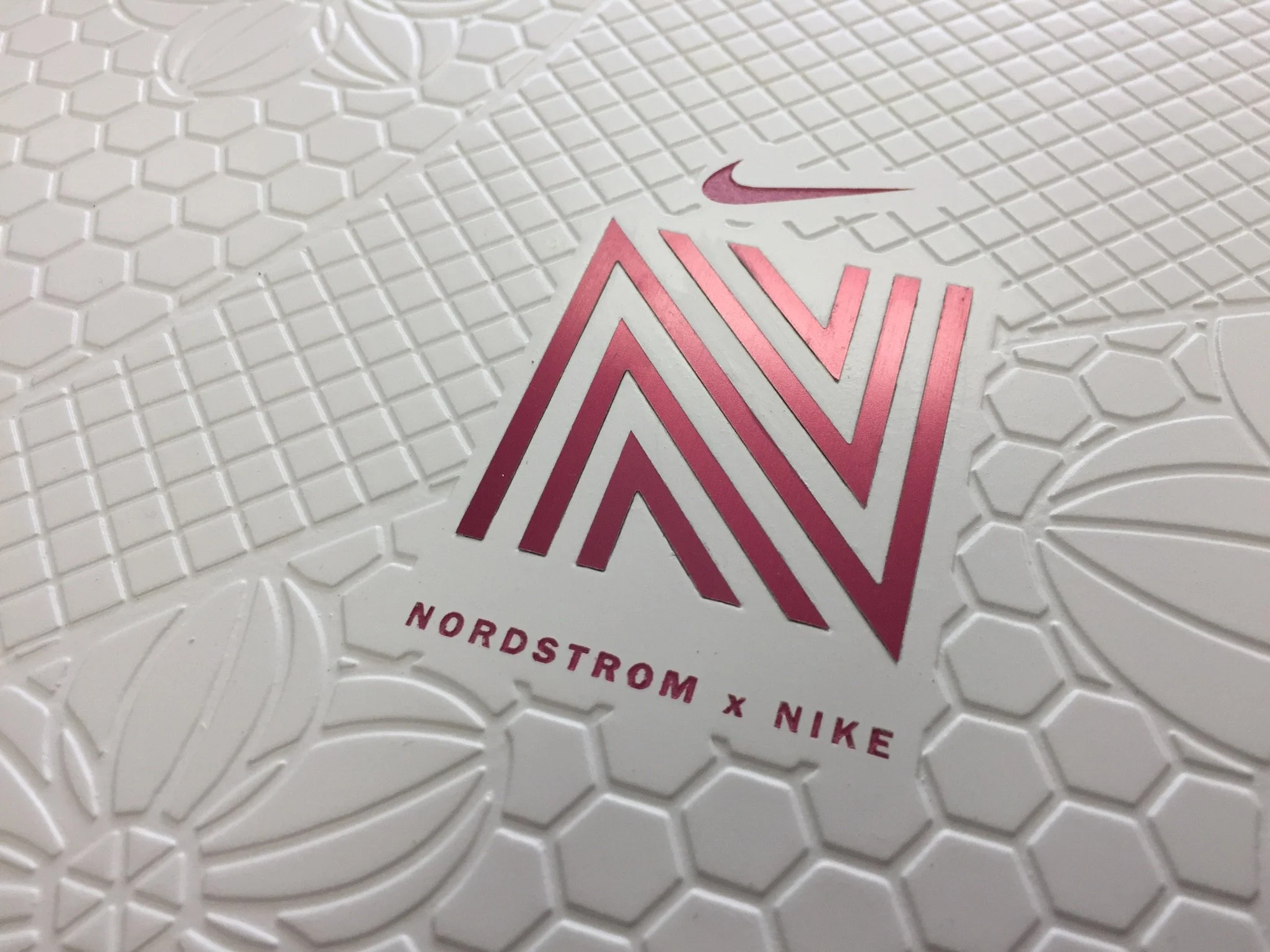 Close-up of the textured surface of a Nike shoebox with the Nike logo in pink and the word 'NIKENORDSTROM' printed below in pink.
