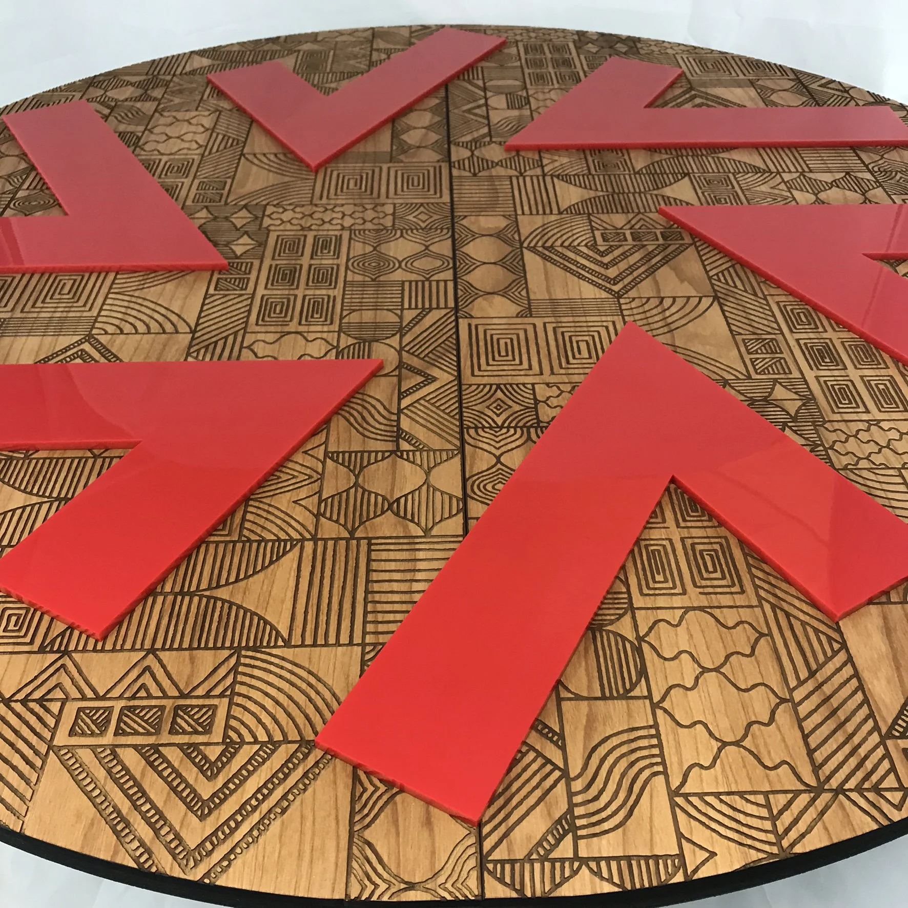 CO2 laser engraved round wooden table with geometric carvings and red plastic alphabet tiles spelling 'YES', custom laser engraving by MC Laser Labs.
