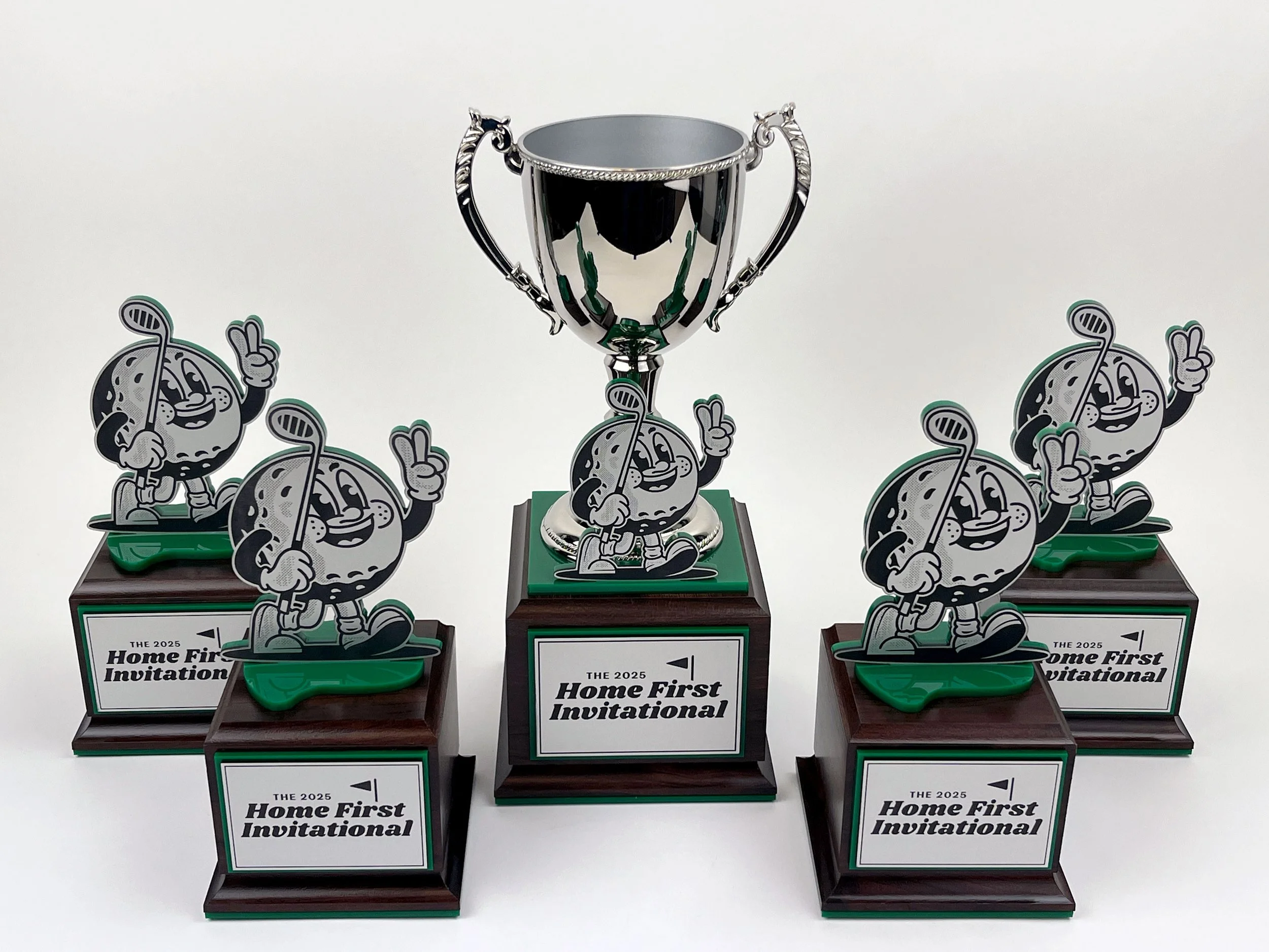 CO2 laser cut and engraved trophies featuring a cartoon golf ball mascot holding a golf club, reading 'The 2025 Home First Invitational', custom fabrication,  laser cutting and engraving by MC Laser Labs.