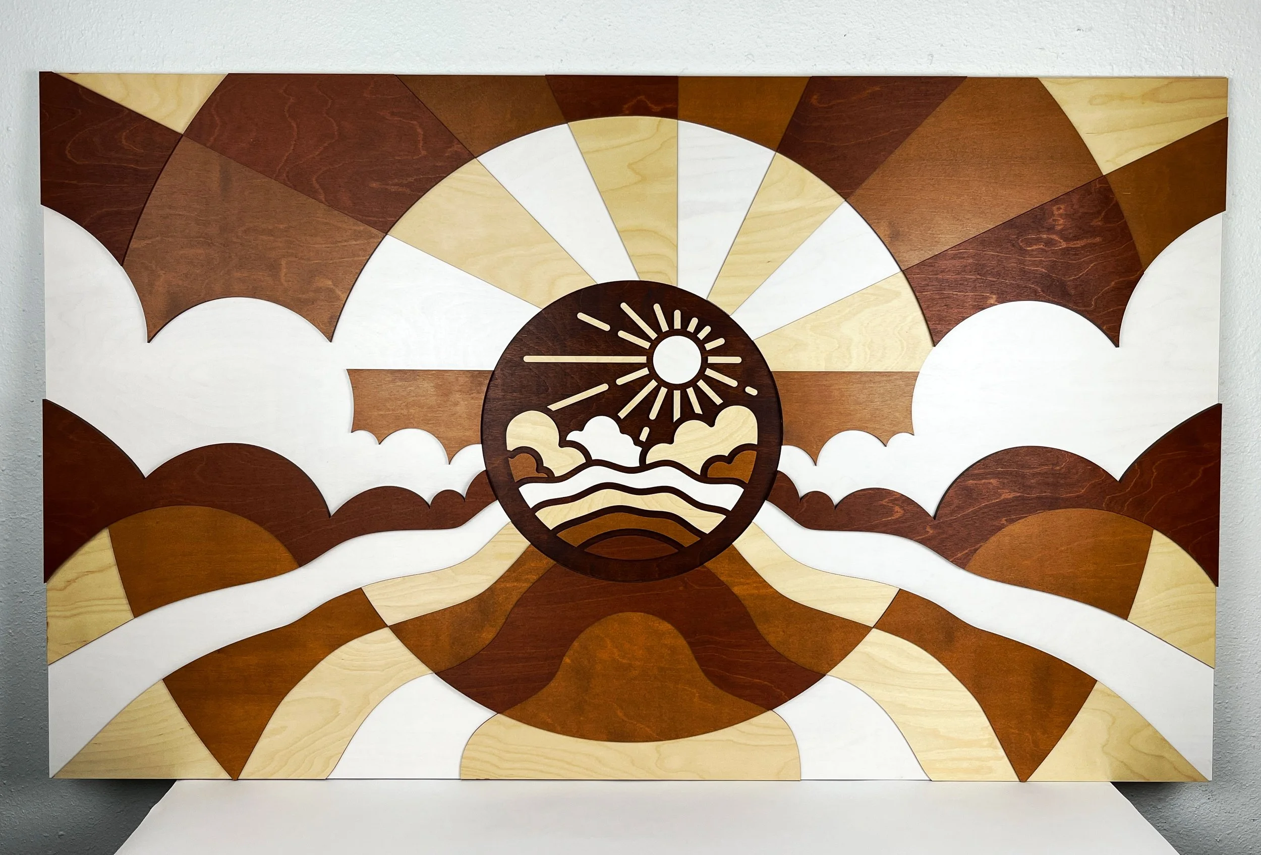 CO2 laser cut and layered stained plywood wall art depicting a sunrise over waves, custom laser cutting by MC Laser Labs.