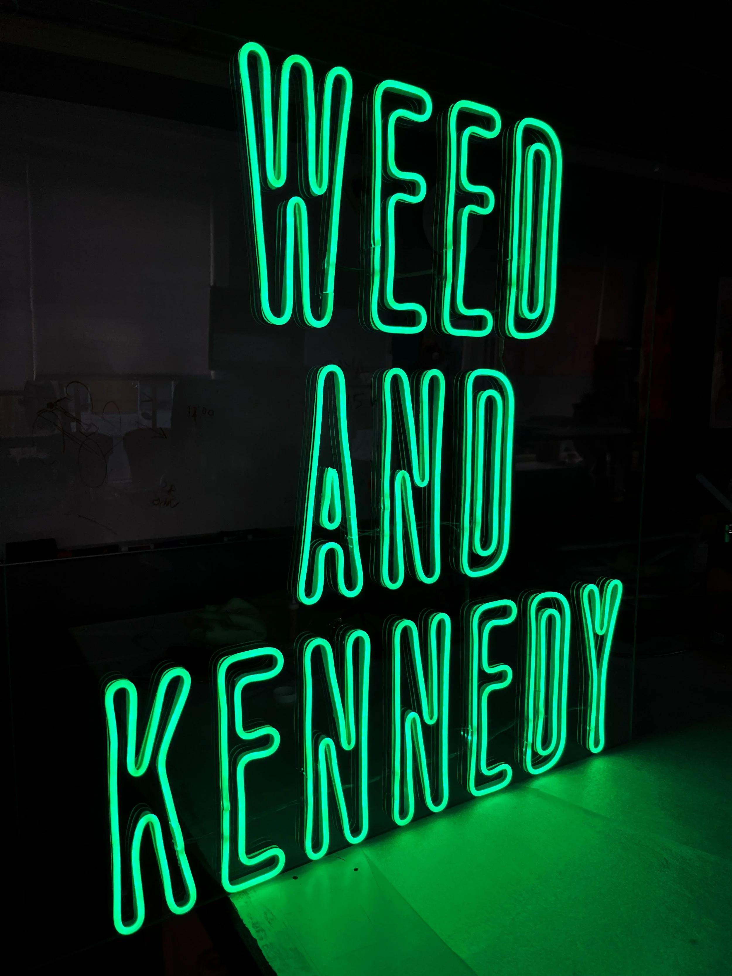 Bright green LED neon sign reading 'WEED AND KENNEDY' for a 420 event at W+K Wieden and Kennedy. MC Laser Labs custom fabrication in Portland Oregon