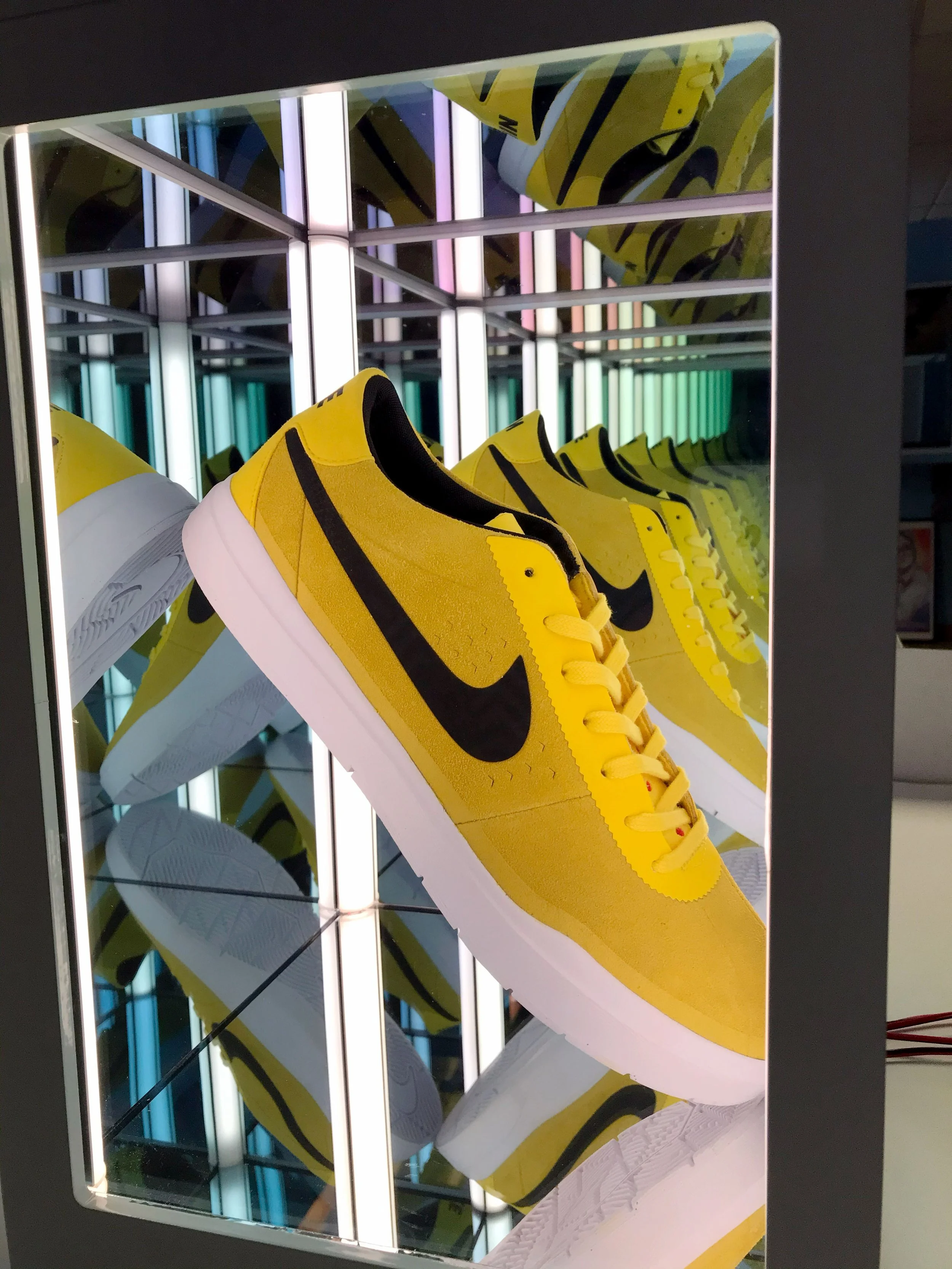 Yellow and black Nike sneakers displayed in and infinity mirror box with led neon lights background, custom retail display fabrication by MC Laser Labs.