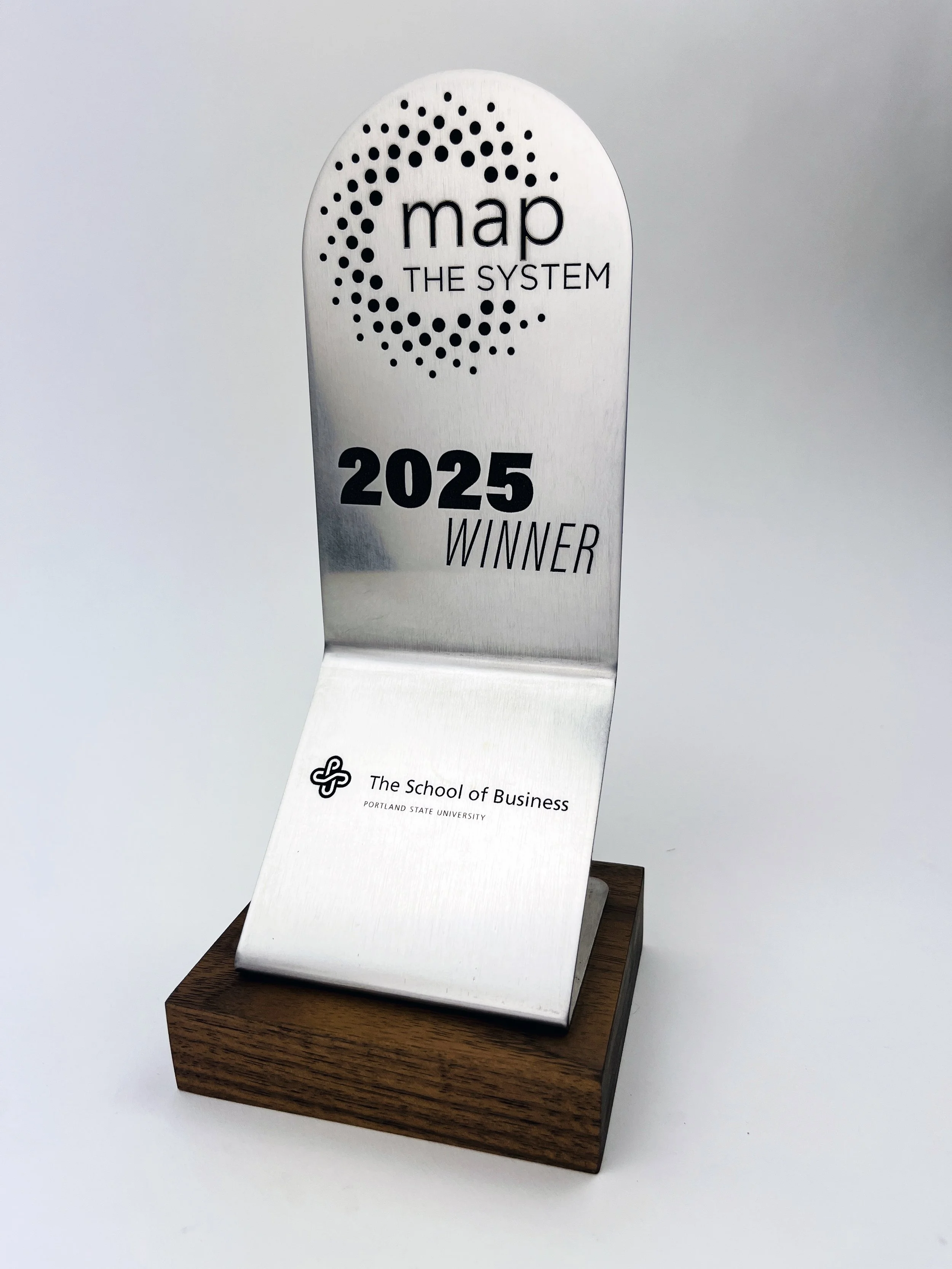 Stainless steel award custom shape and bending. Fiber laser engraved 'MAP THE SYSTEM 2025 WINNER' with The School of Business at Portland State University logo, custom metal laser engraving by MC Laser Labs.