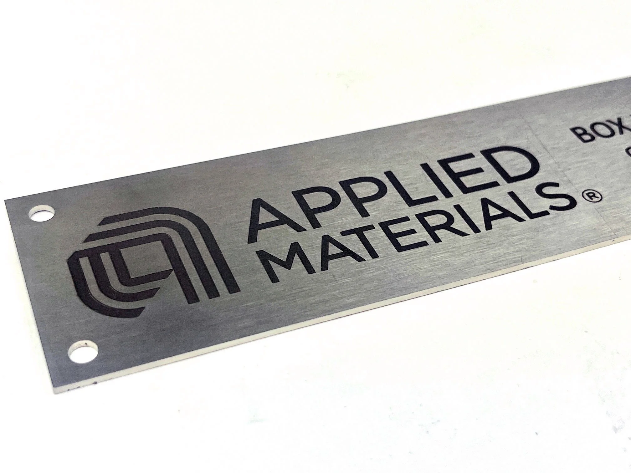 A metallic label with holes at the corners reading 'Applied Materials'.