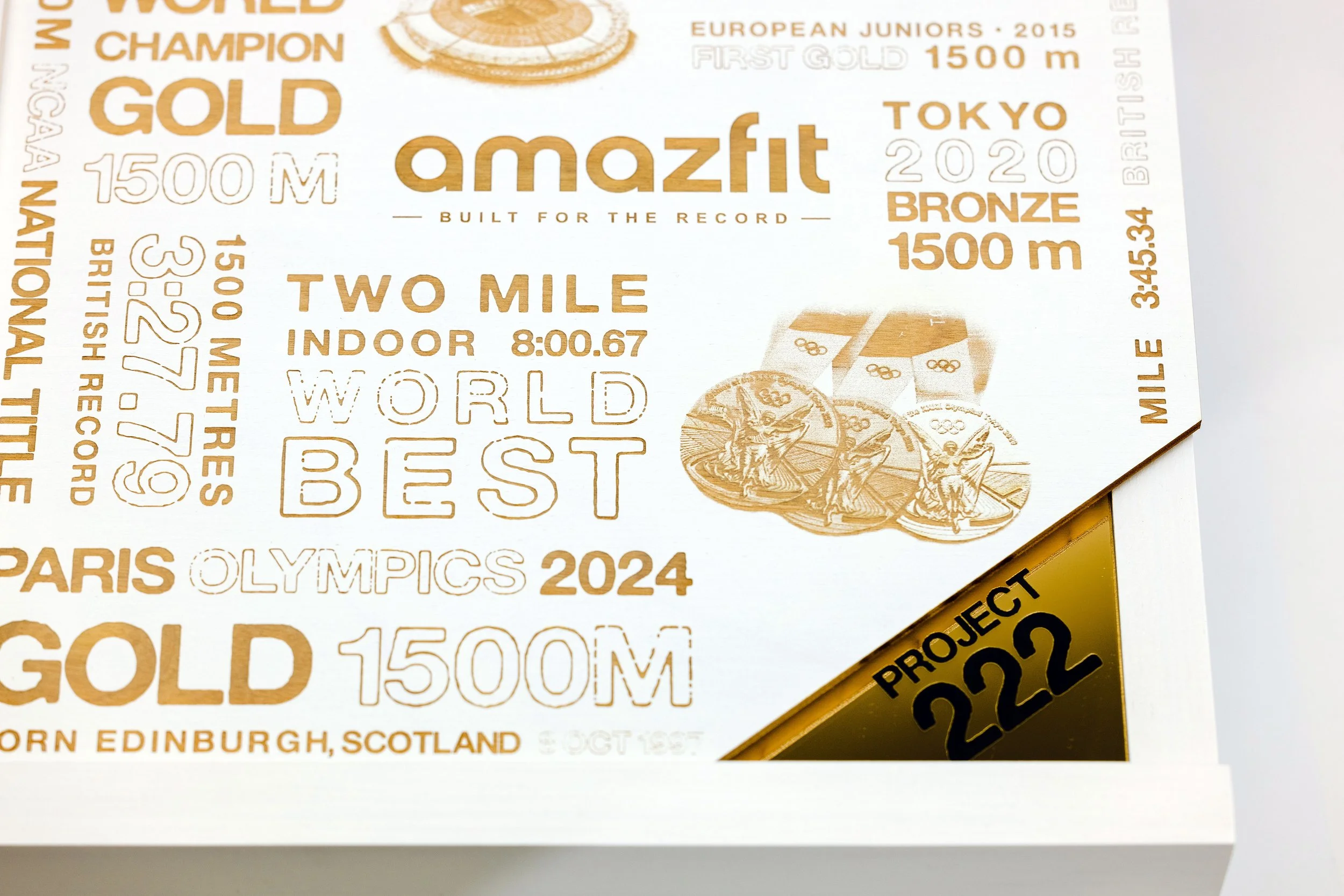 Printed poster from the Josh Kerr Amazfit smartwatch seeding kit box, featuring gold and bronze medal graphics and record-breaking Olympics and European Juniors achievements, custom fabrication by MC Laser Labs.