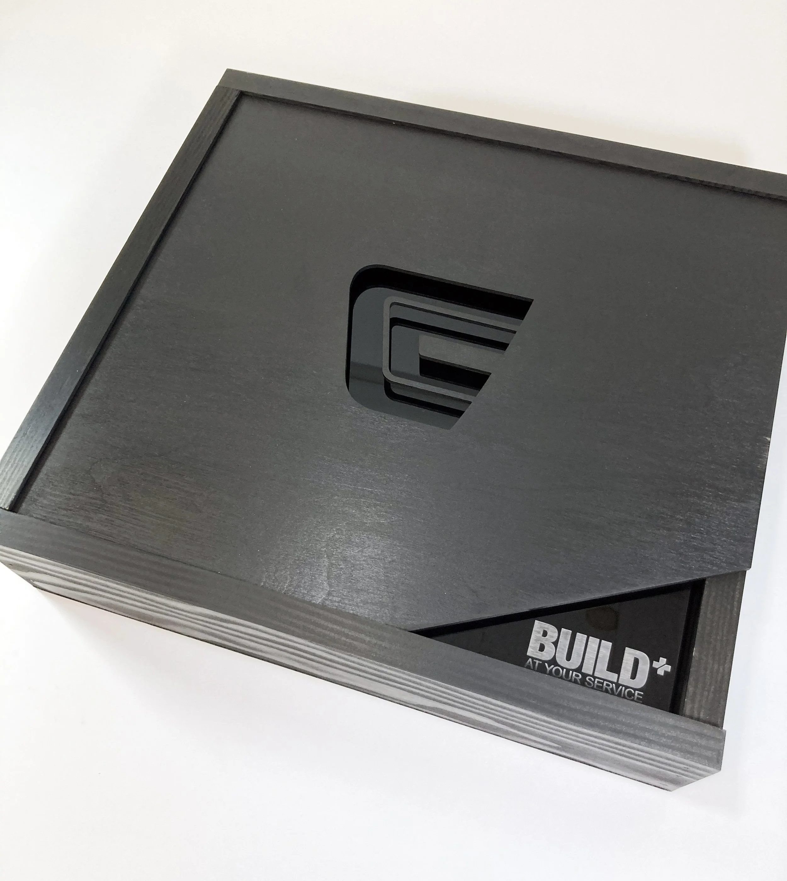 Wood stained black seeding kit box for Centrex Construction reading 'BUILD' and 'AT YOUR SERVICE', custom fabrication by MC Laser Labs.