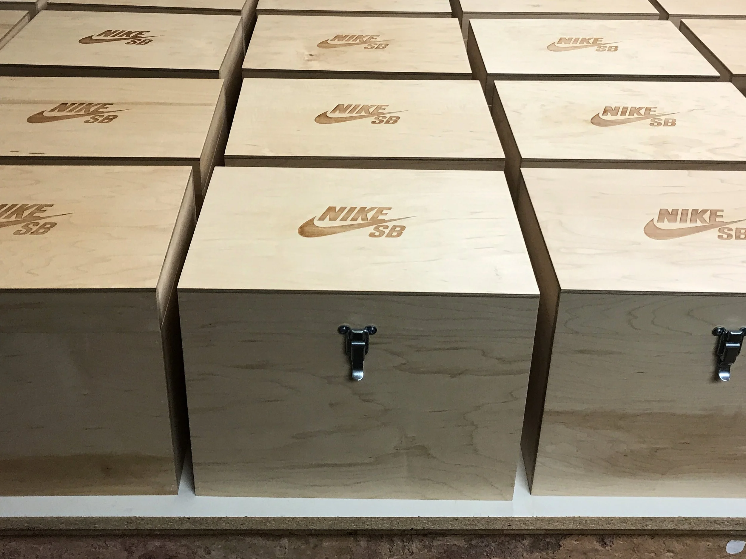 CO2 laser engraved light-colored wooden shoeboxes with the Nike SB logo, arranged in rows, custom laser engraving by MC Laser Labs.