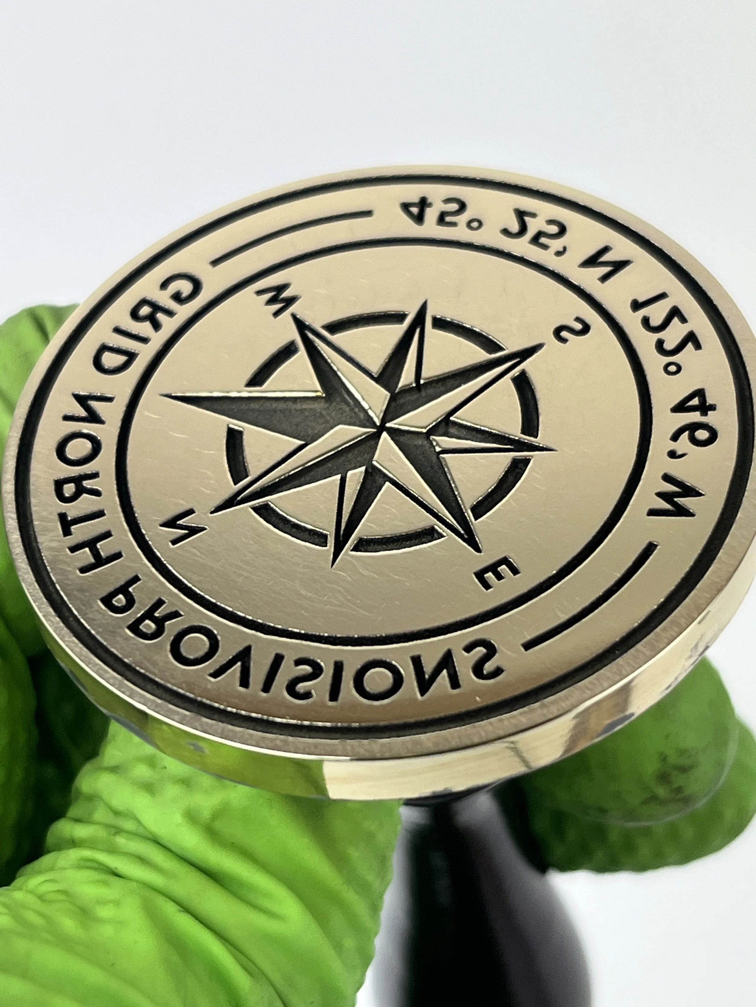 Close-up of a silver compass held by green lettuce leaves, with a white background.
