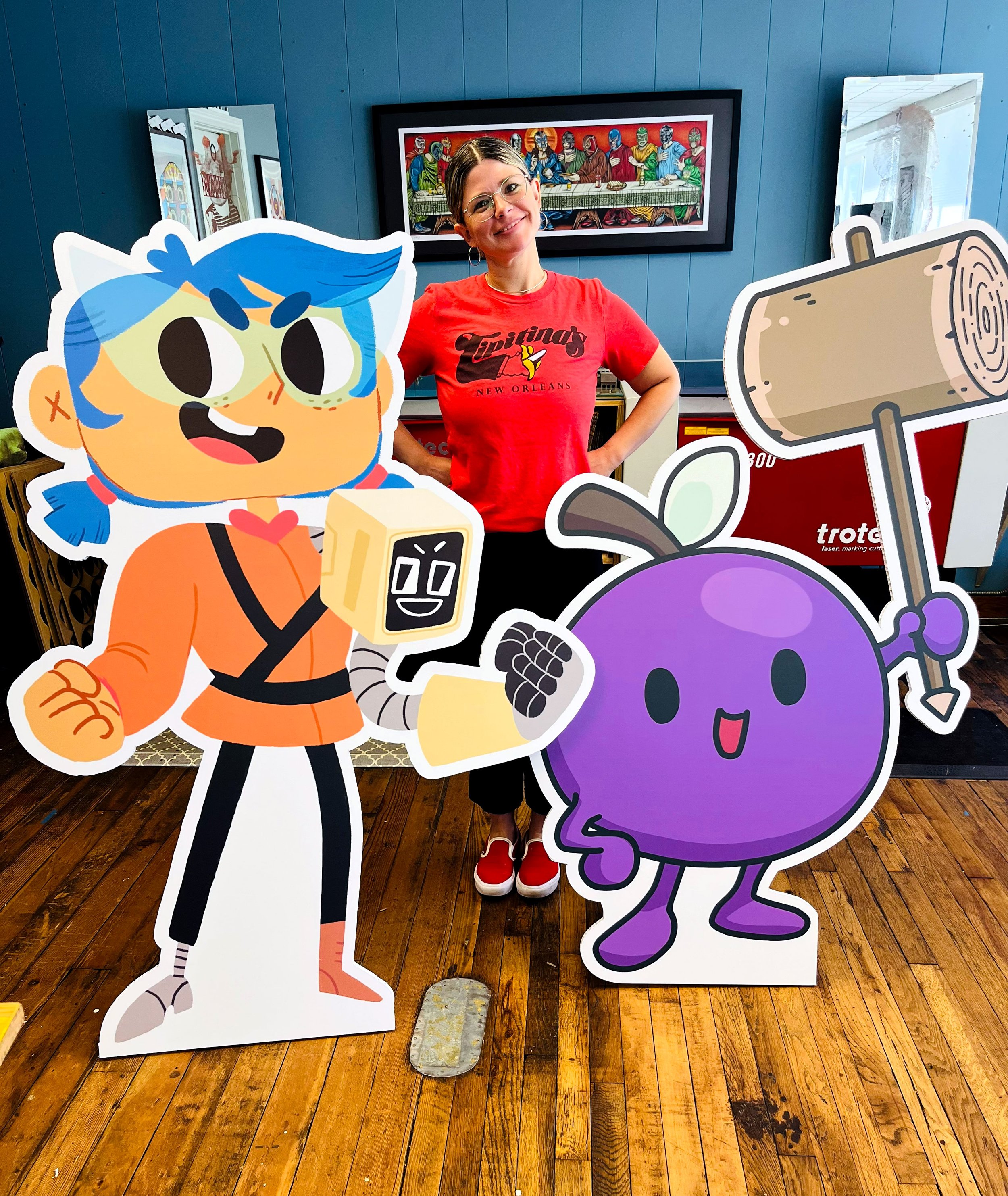 CO2 laser engraved maple with printed and cut acrylic, featuring a woman standing behind cartoon character cutouts, custom laser engraving and printing by MC Laser Labs.