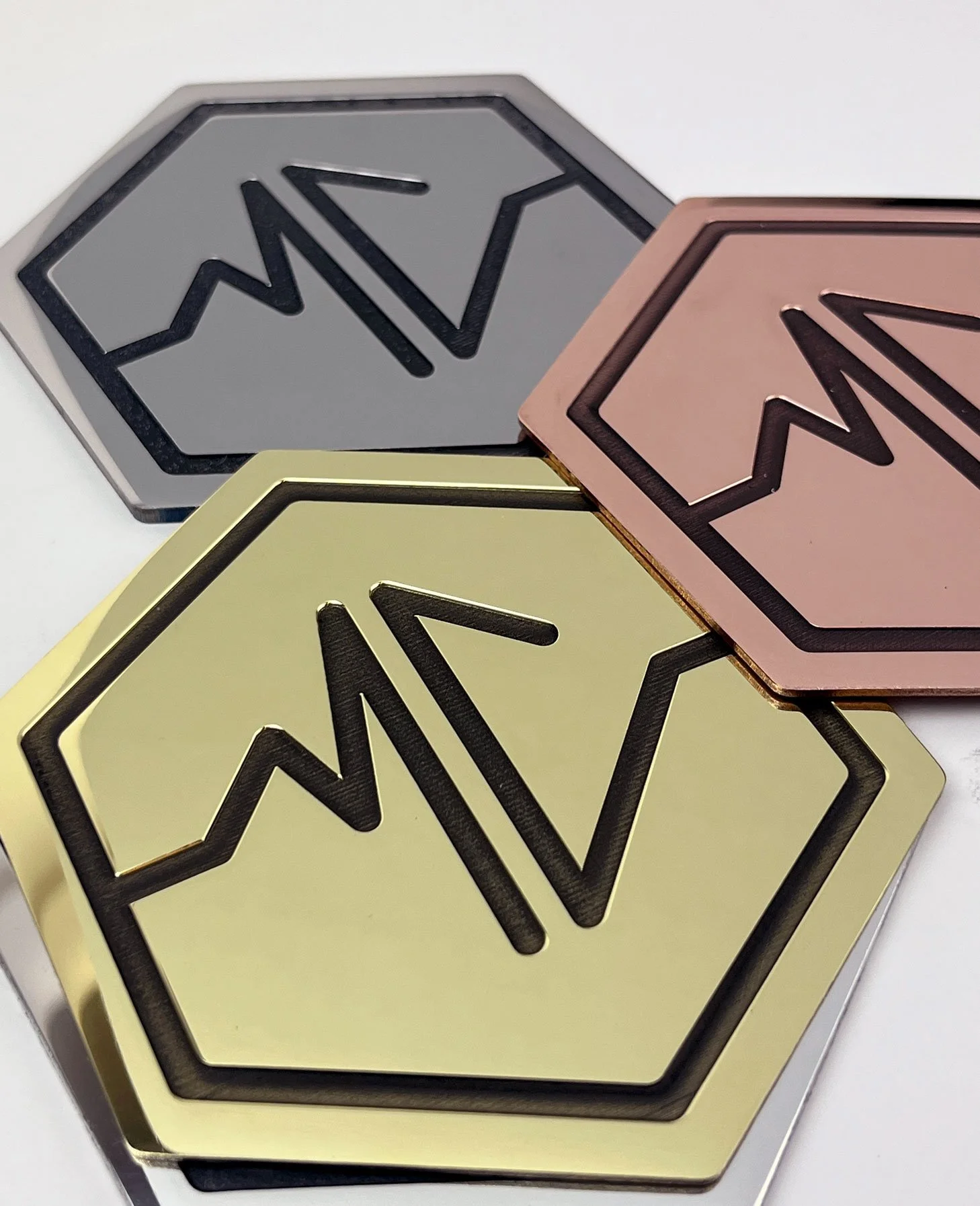 Three metallic boxes with hexagon-shaped logos. The boxes are in gray, pink, and gold colors.