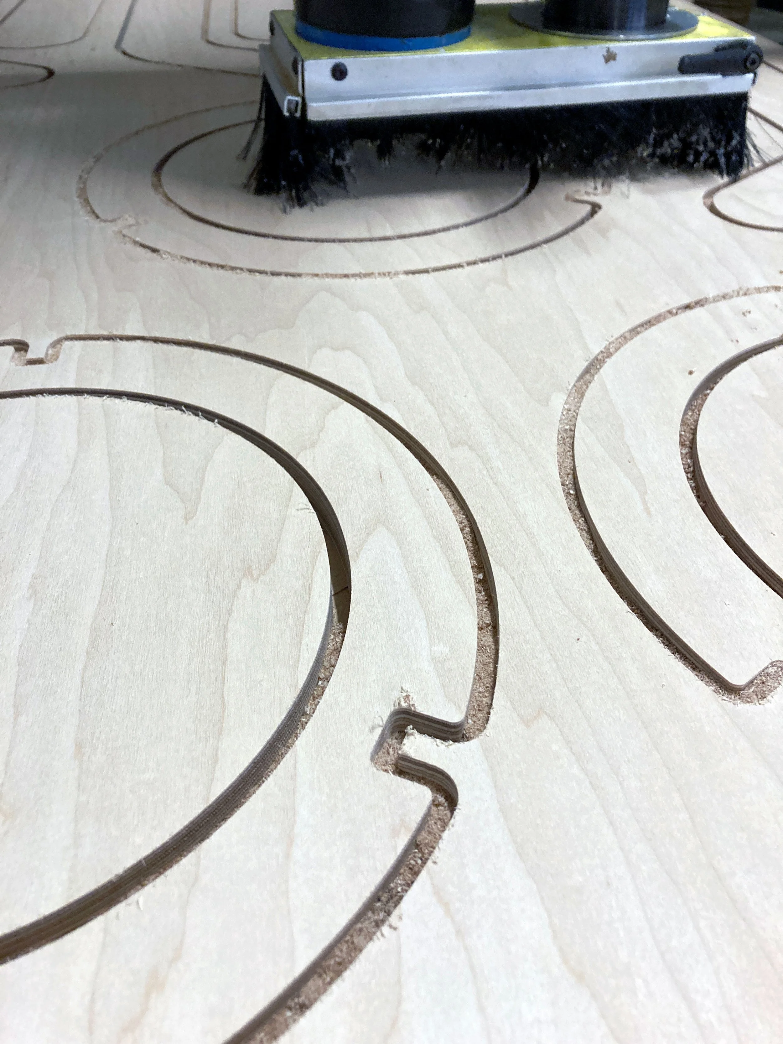 A robotic vacuum cleaner with brushes underneath, moving on a hardwood floor with concentric circles etched into it.