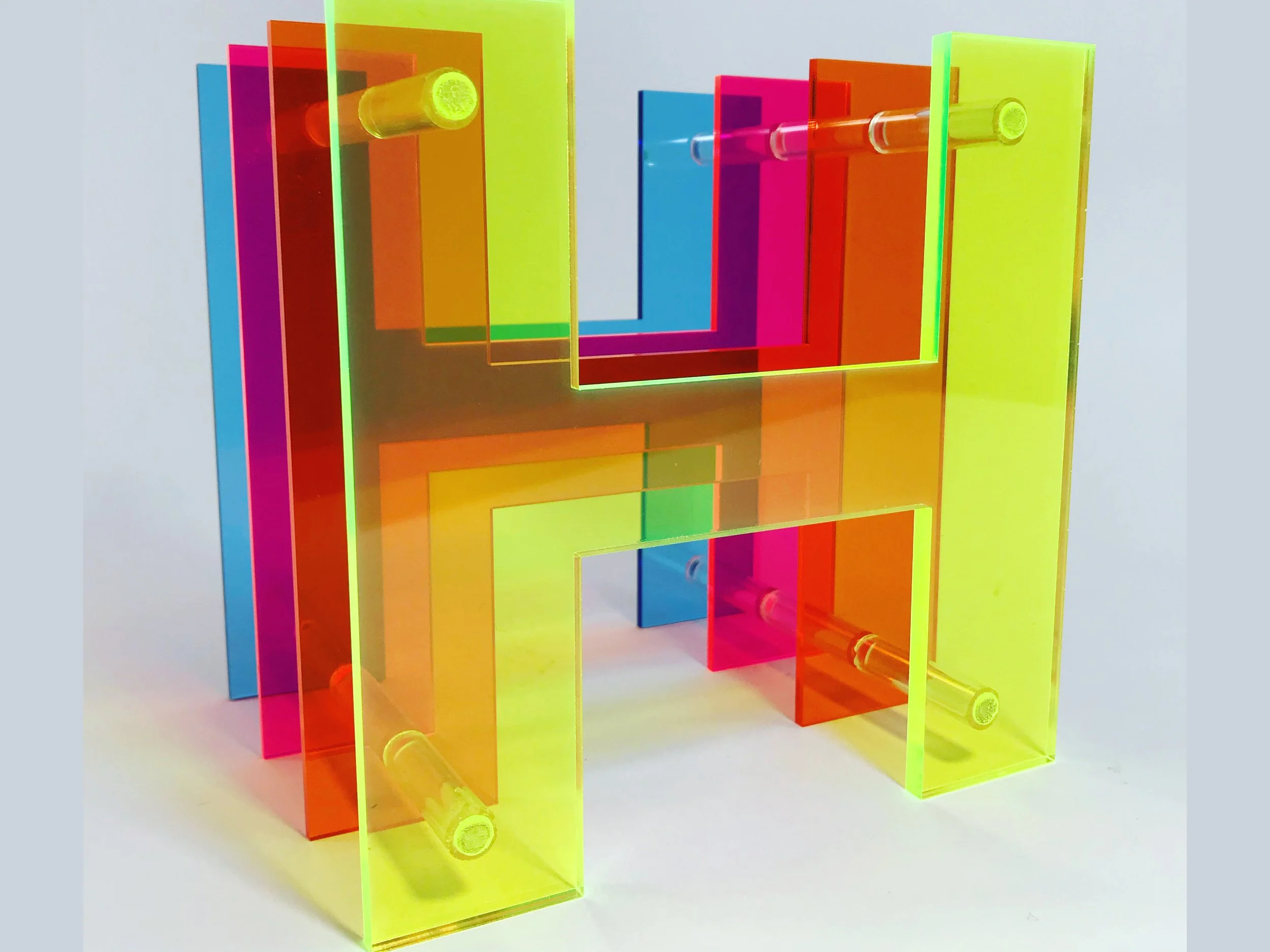 CO2 laser cut colorful acrylic shelving units in yellow, orange, pink, blue, and green in a modern geometric design, custom laser cutting by MC Laser Labs.