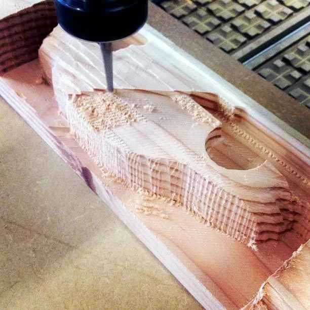 CNC router carving detailed decorative patterns into layered pink foam, custom CNC routing by MC Laser Labs.