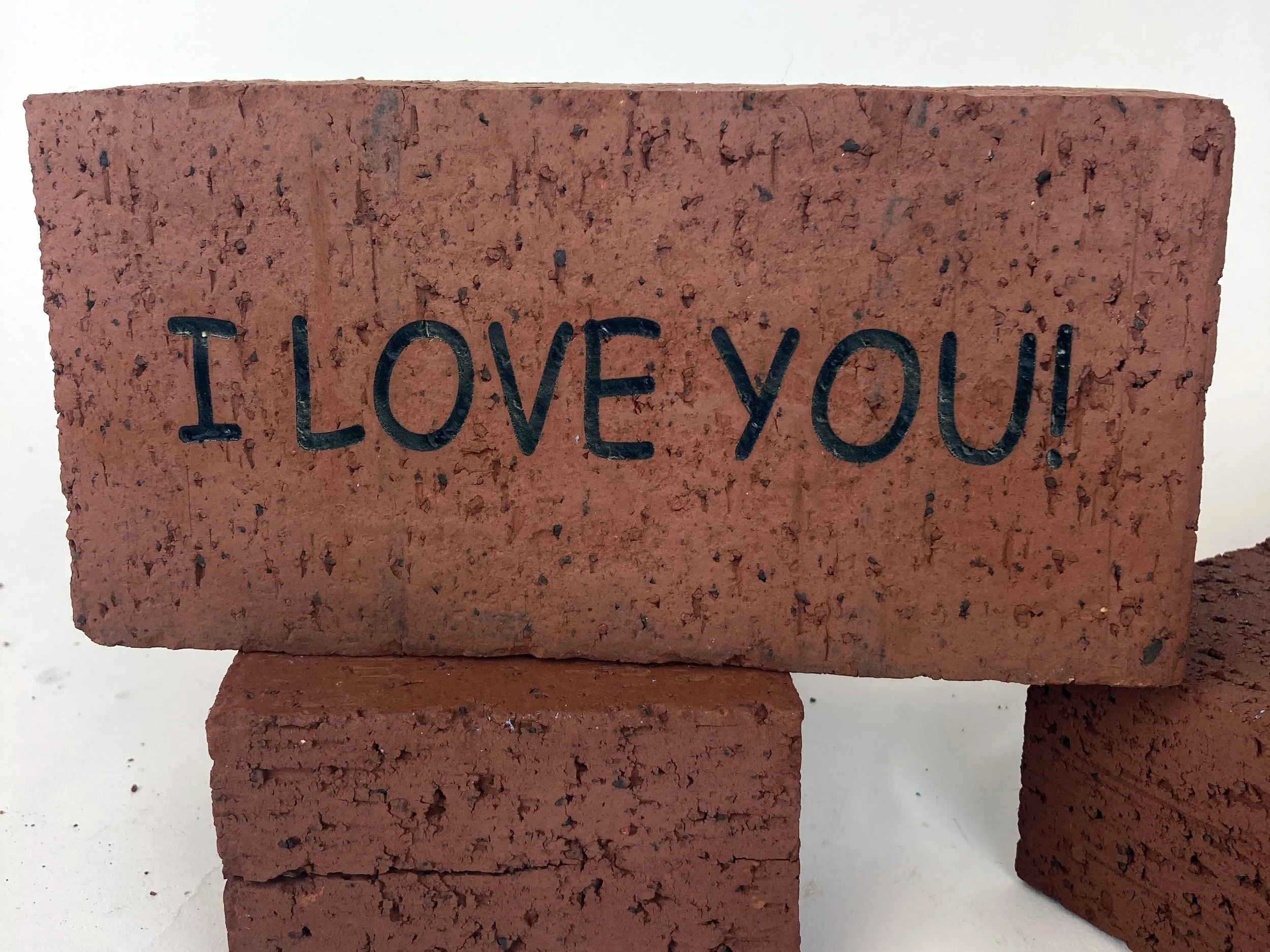 Fiber laser engraved red clay bricks reading 'I LOVE YOU', custom brick engraving by MC Laser Labs.