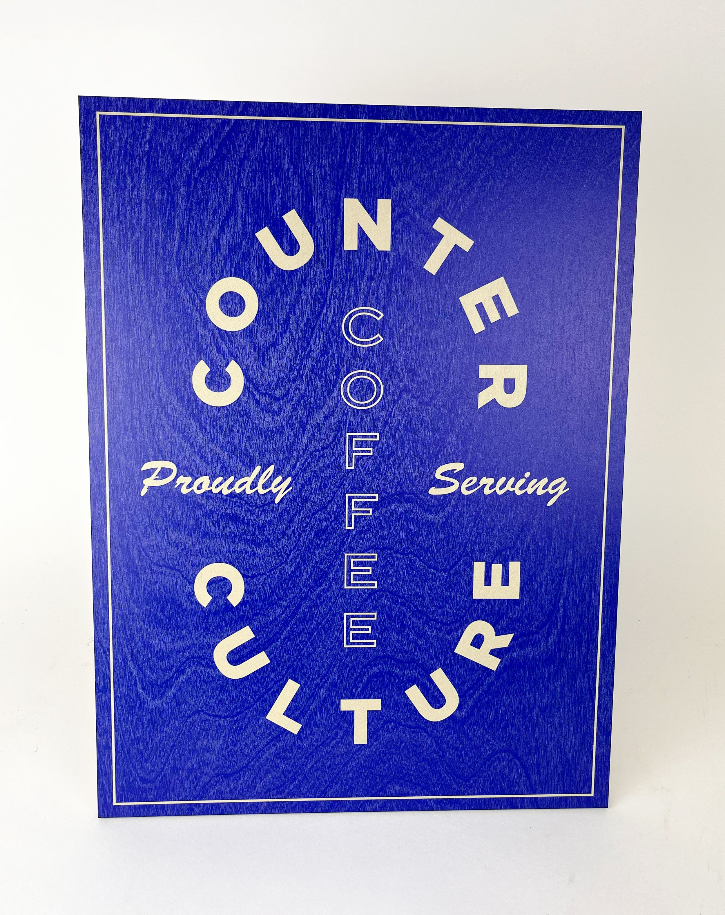 A blue flyer with white text that reads "COUTURE" in a circular arrangement and "Proudly Serving" at the bottom.