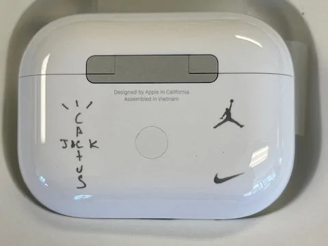 A white rectangular airPods case with doodles and text, including a basketball, a jumping person, and the Nike swoosh logo.