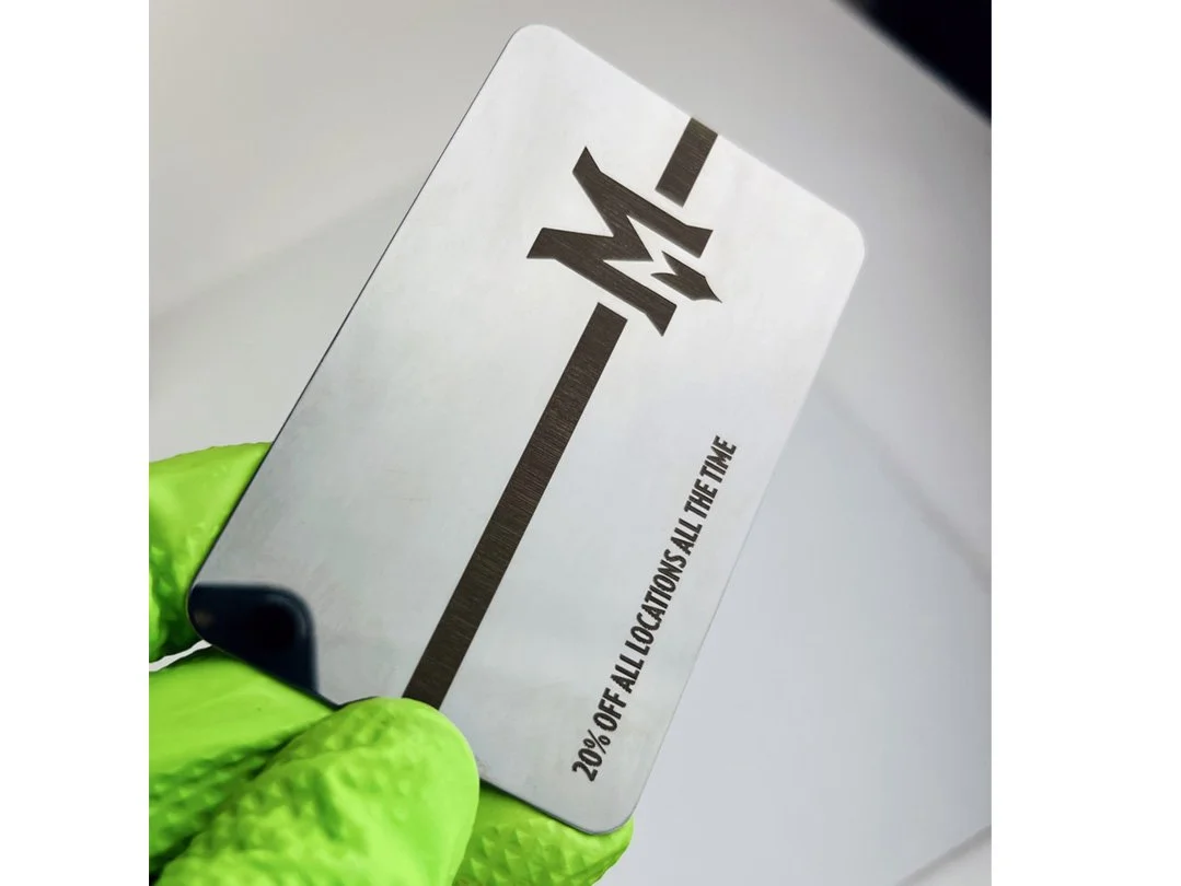 Gift card with '20% off all locations all the time' message, held by a person wearing a bright green glove.