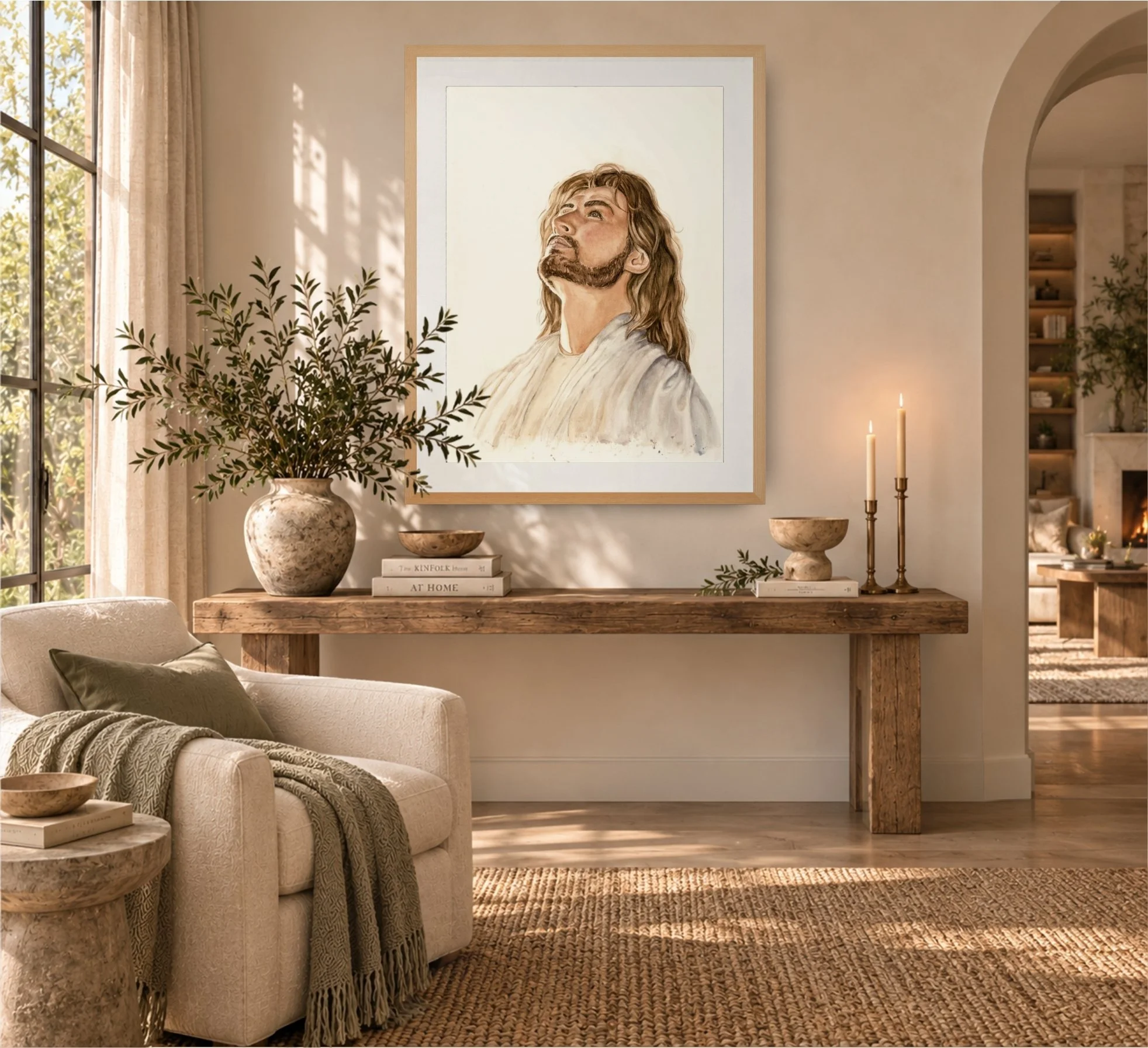 Cozy living room with a beige sofa, knitted throw blanket, and scatter pillows. A side table with a book and bowl. Large framed portrait of a bearded man with long hair is hanging on the wall, illuminated by natural light from a nearby window. Decor includes potted plants, books, and two candles on a wooden console table.