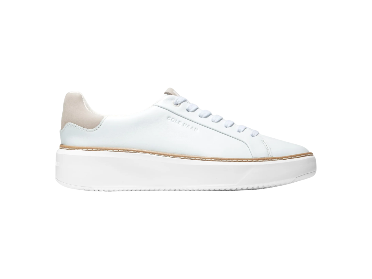 White sneaker with beige accents and a thick sole, labeled 'Cole Haan' on the side, isolated on a white background.