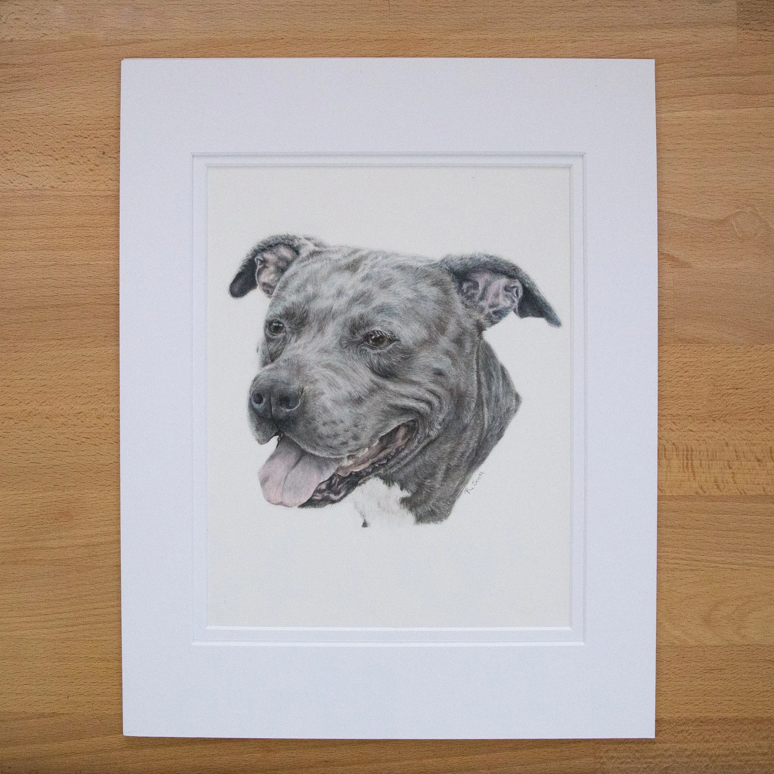 A watercolor portrait of a dog, possibly a labrador, on a white piece of paper placed on a wooden surface.