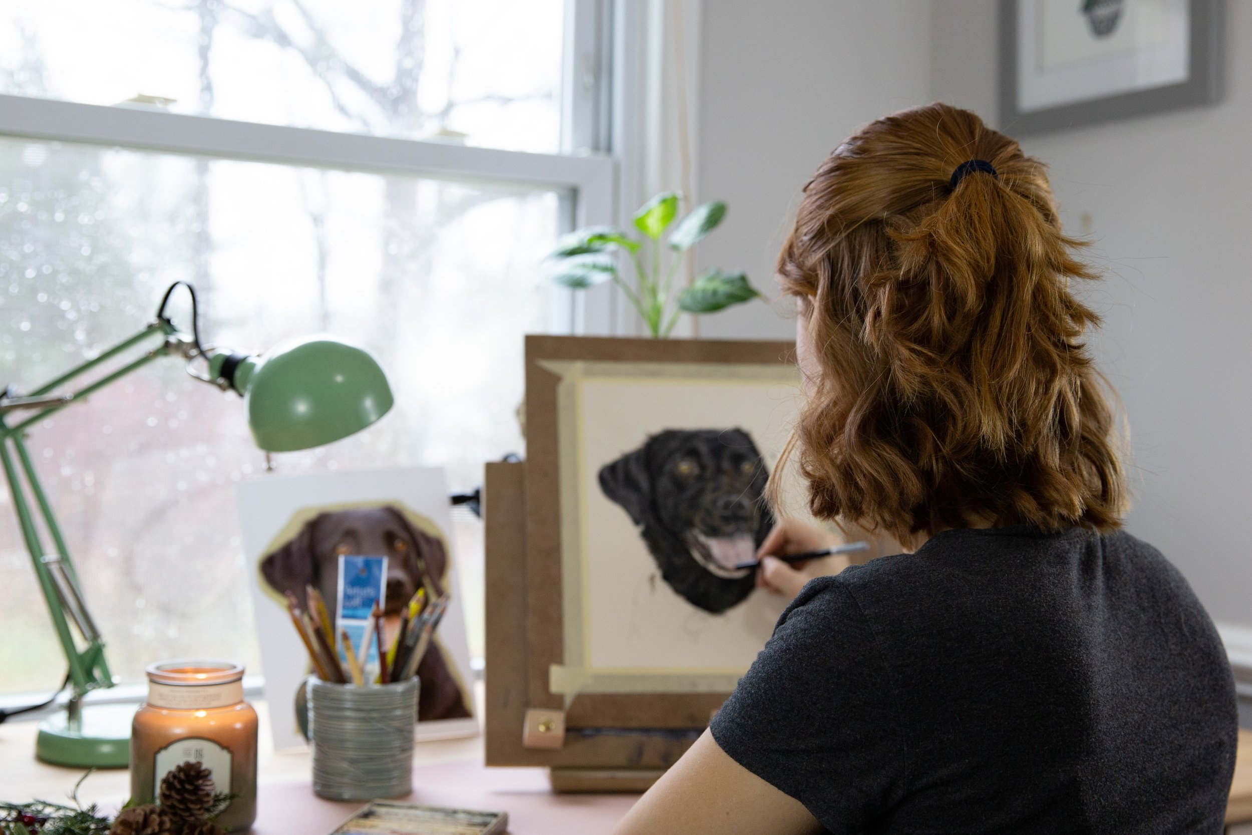 Rebecca is working on a highly realistic custom pet portrait of a black dog in pastels and colored pencils.