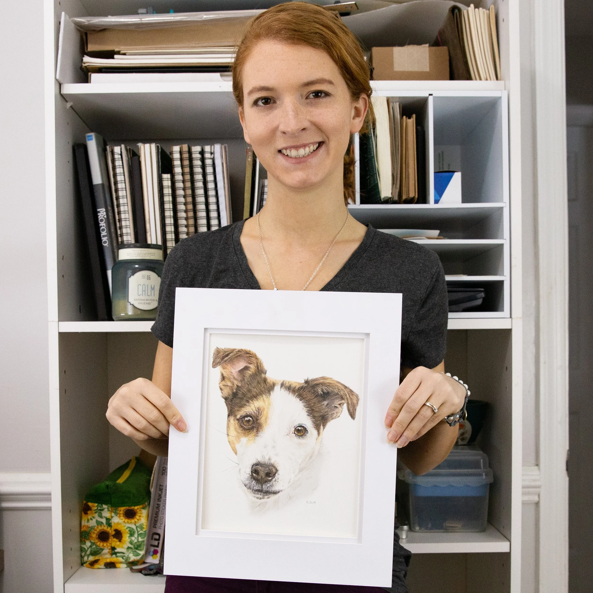 Rebecca is holding an example custom pet portrait commission in double matting before being sent to client.