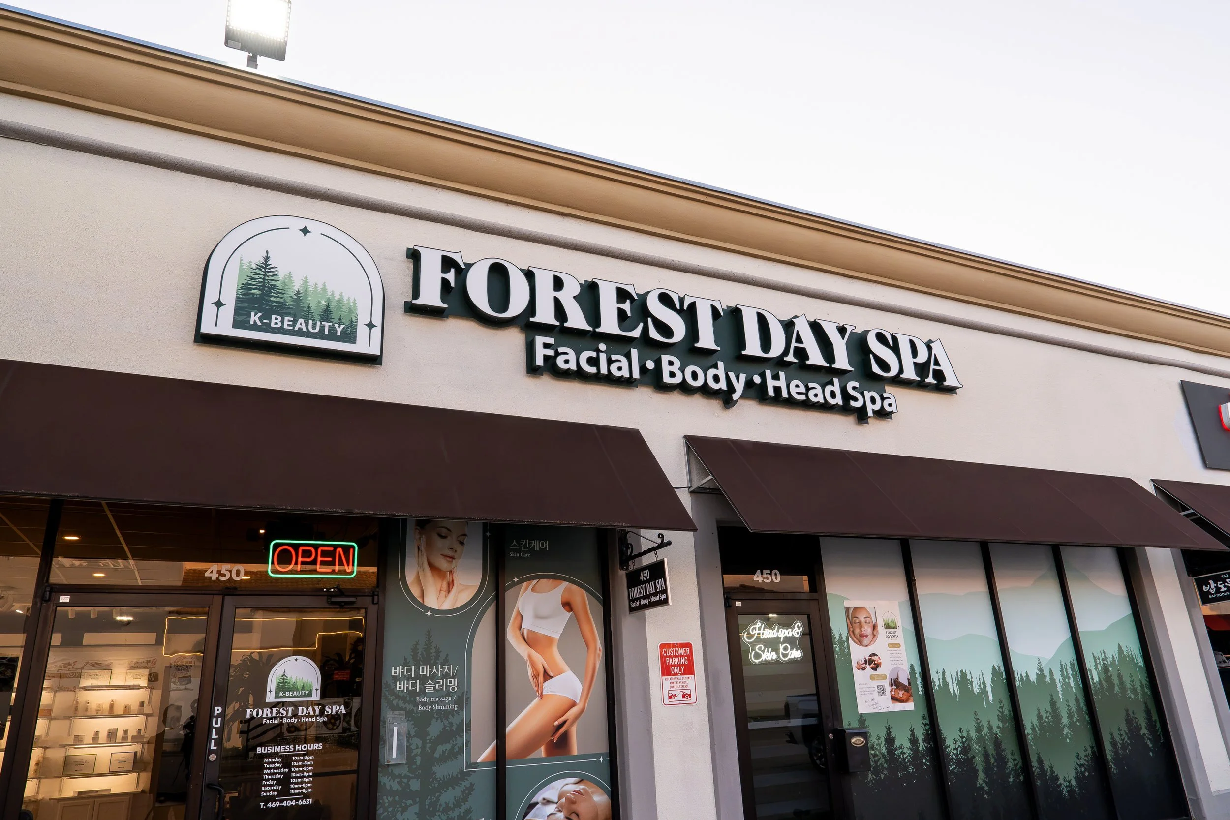 Exterior view of Forest Day Spa with signage including services like facial, body, and head spa, and a neon 'Open' sign in the window.