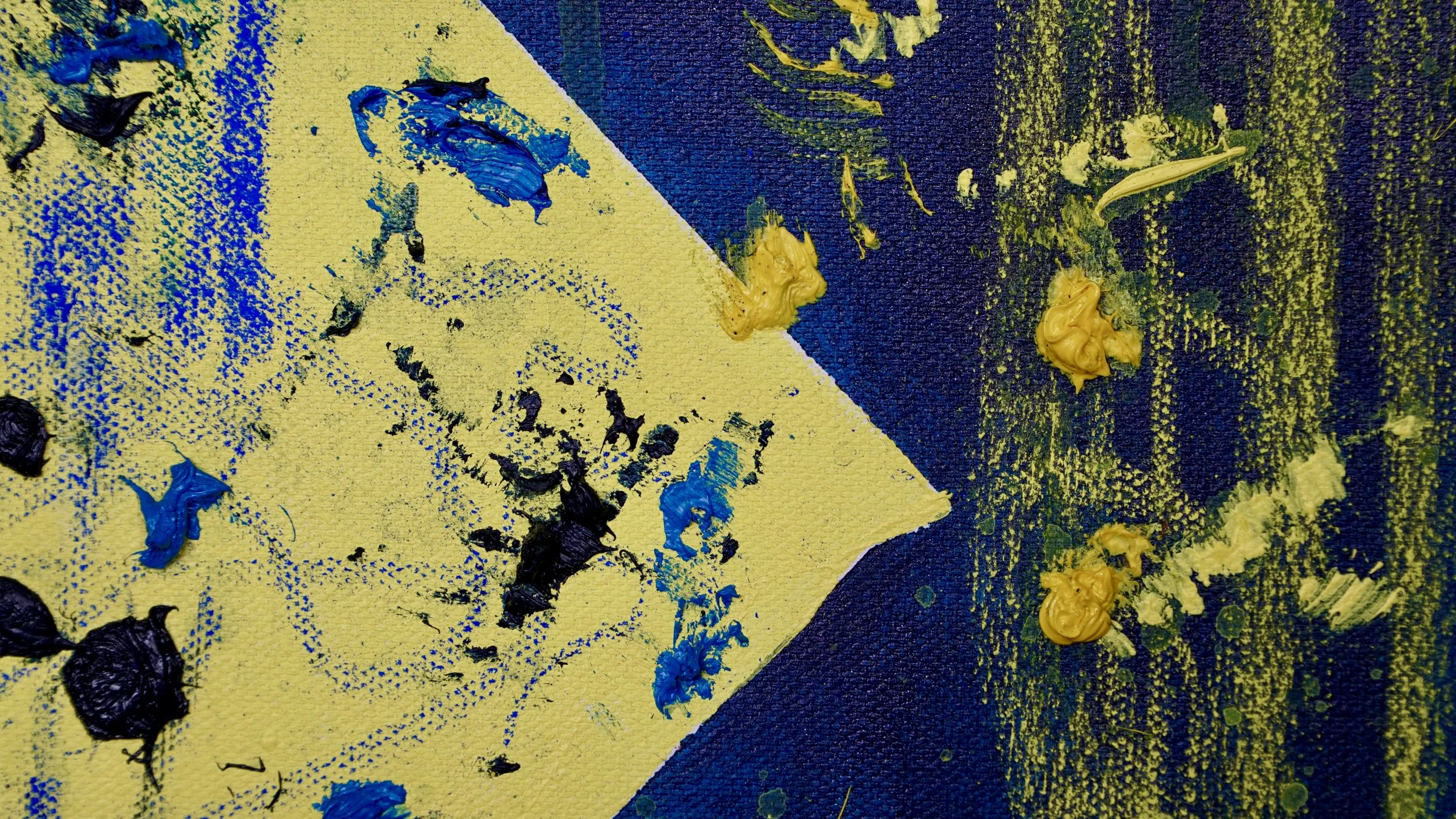 Close-up of an abstract painting featuring blue, yellow, and black paint splatters and textured brushstrokes on a canvas.