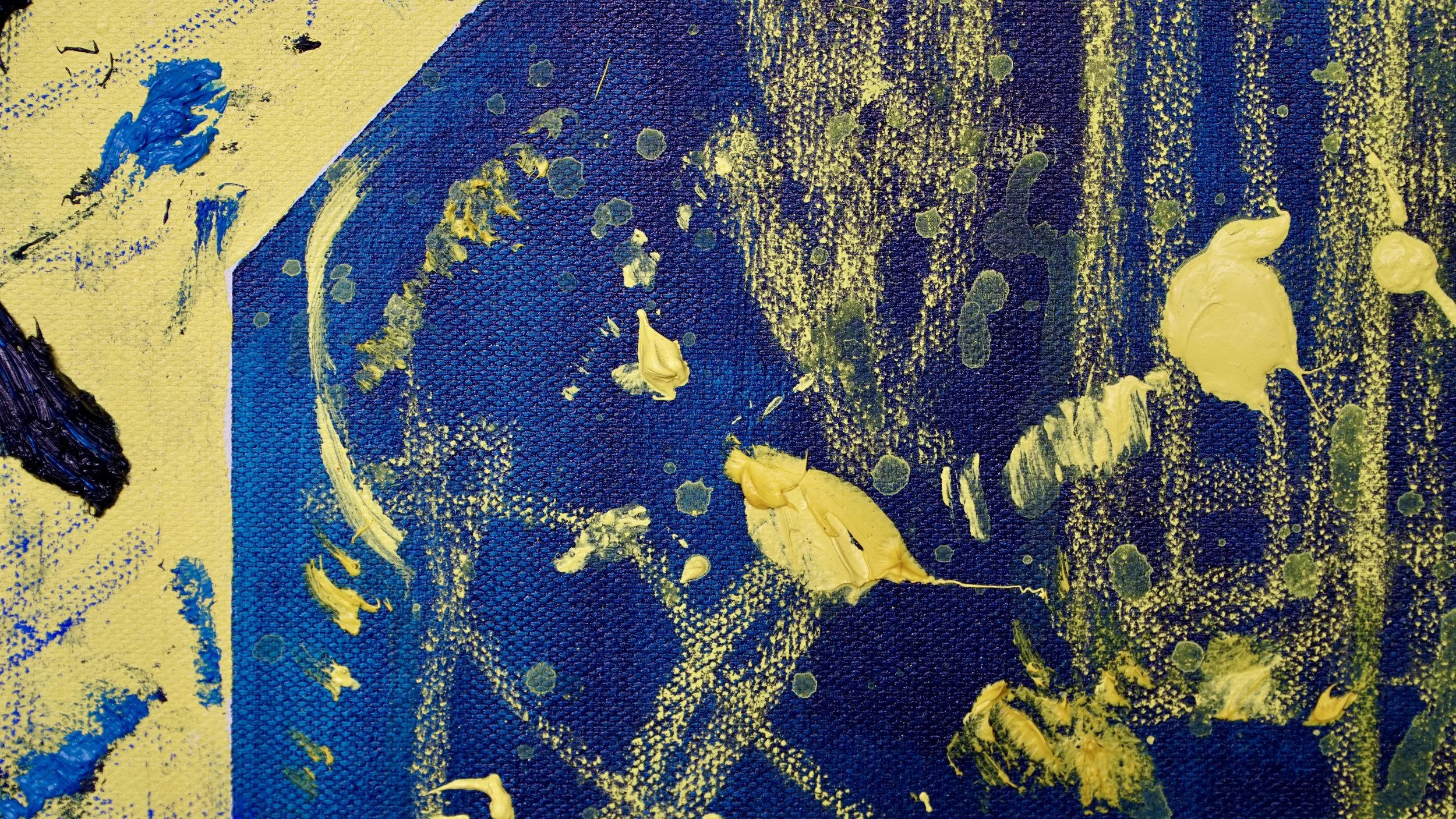 Close-up of an abstract painting with blue and yellow acrylic paint splatters and strokes on a textured canvas.