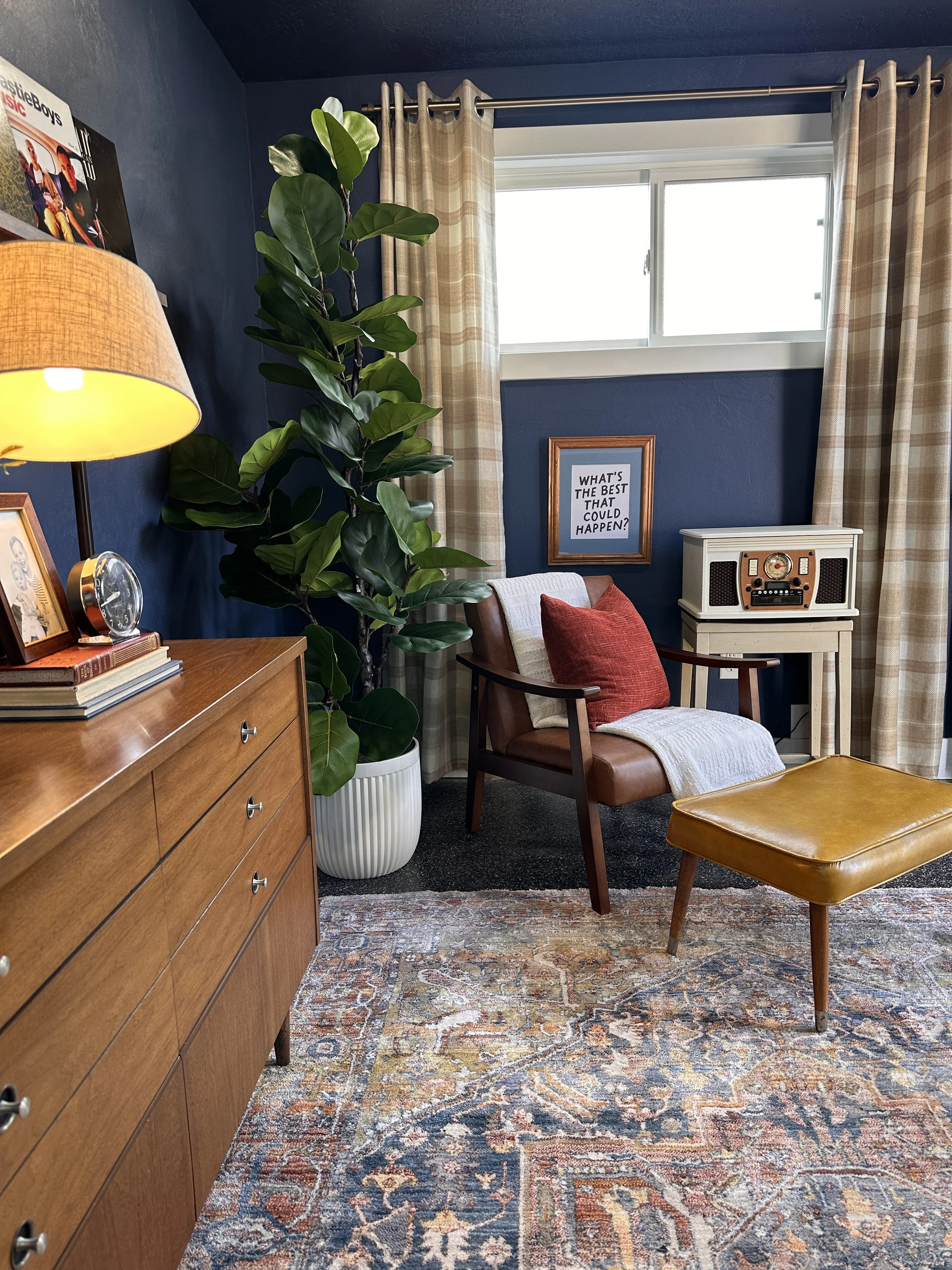 Navy reading nook with wood dresser, fiddle leaf fig, and leather accent chair