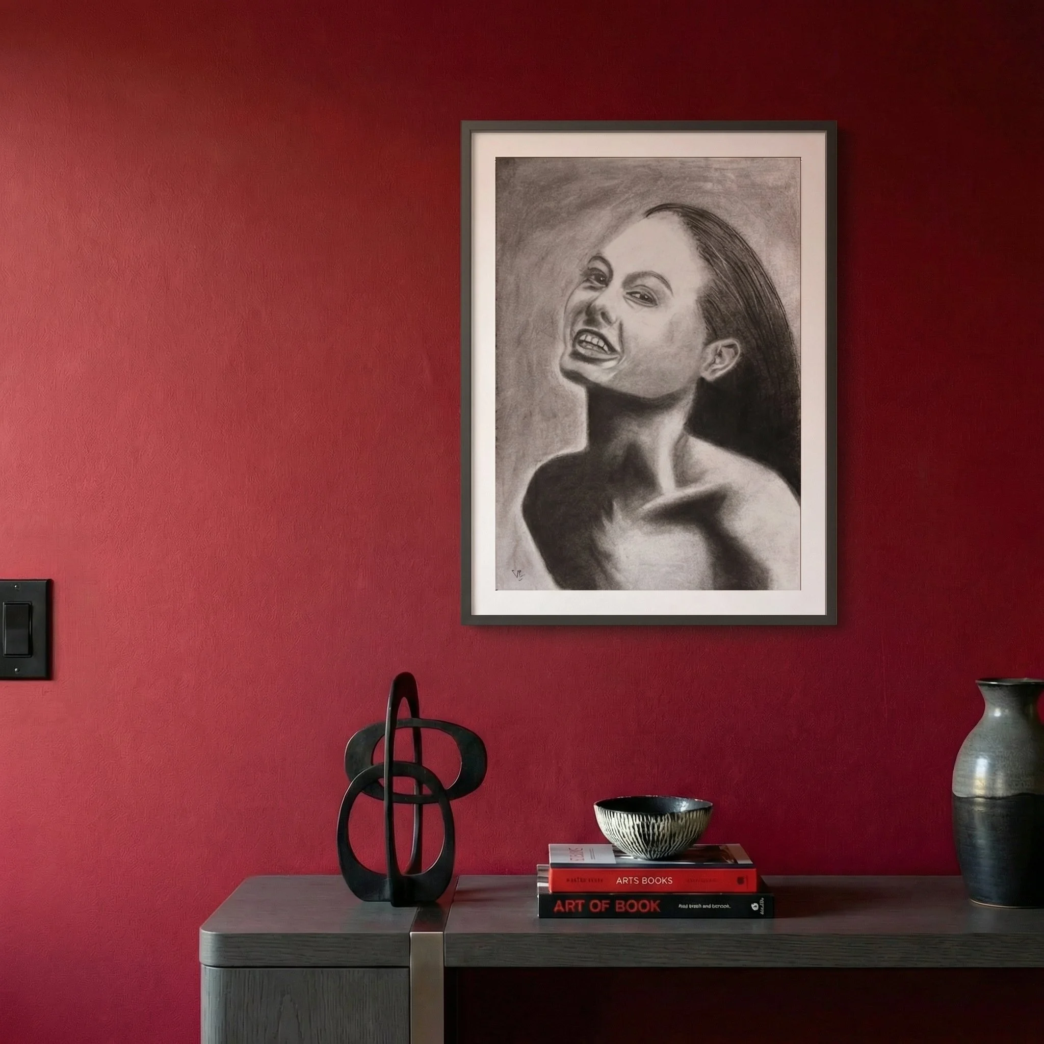 Framed She Laughs Anyway displayed above a dark console against a deep red wall in a contemporary interior.