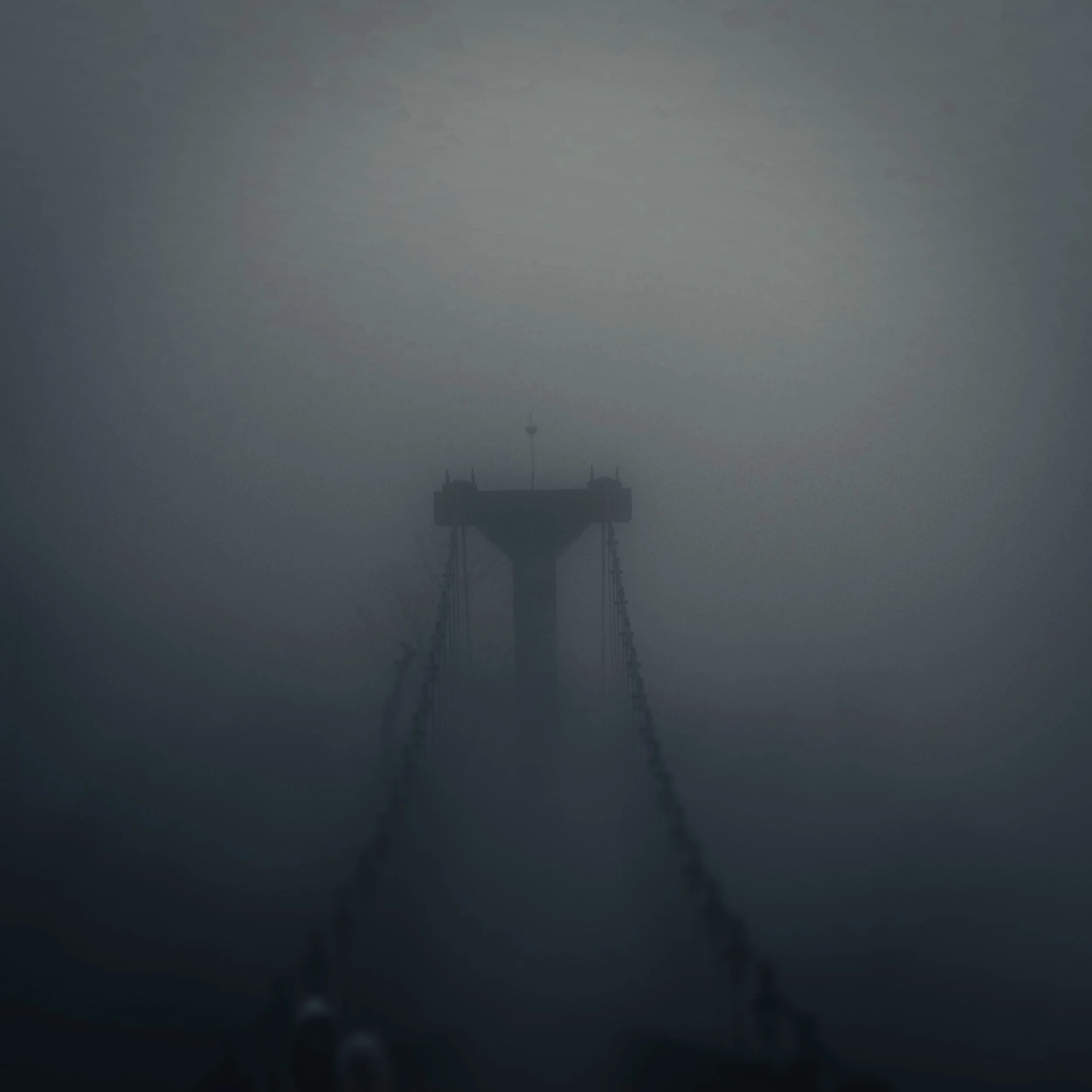 The tip of a bridge peeking out from the fog