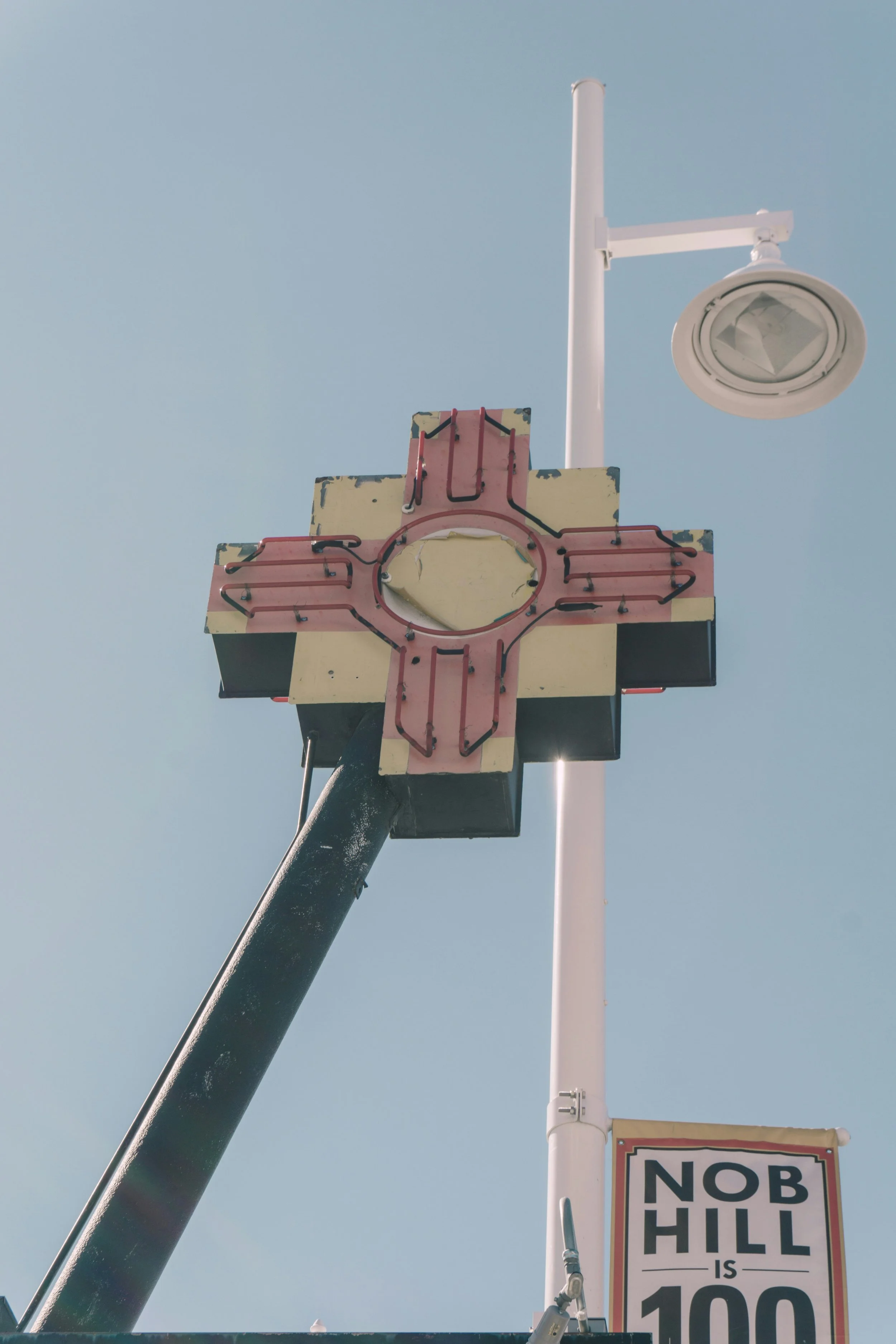 A street sign showing Nob Hill, with a traffic light pole and a street lamp against a clear blue sky.