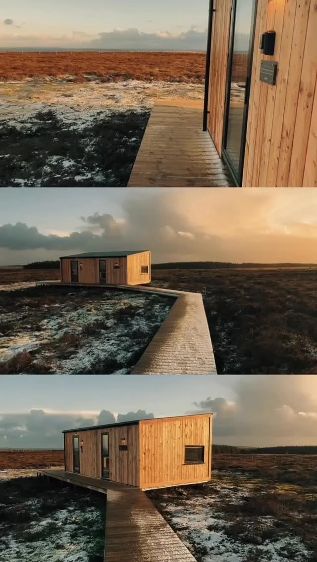 Remote cabins connected by a timber path beneath a dramatic sky.