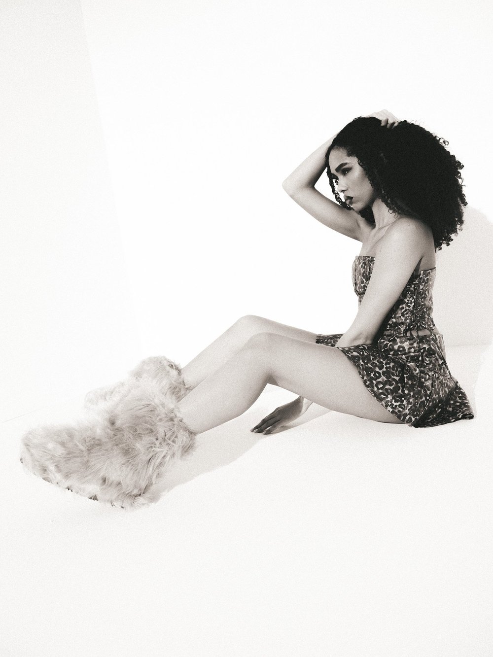 Leopard mini dress, seated studio pose with textured slippers. Photography by CAMR Visuals.