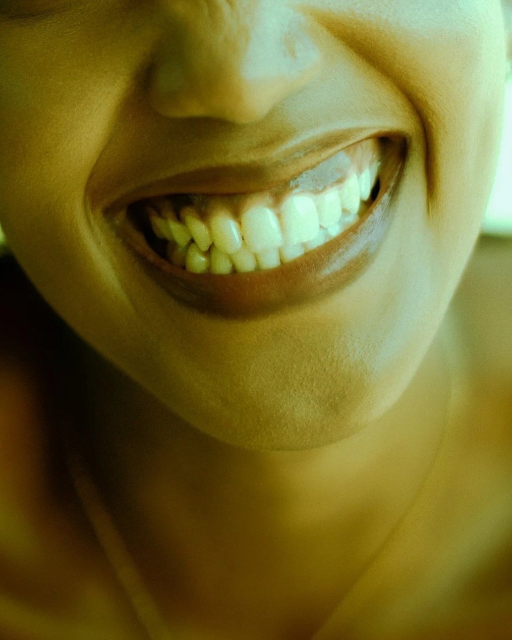 Close-up of a person's smiling mouth showing teeth.