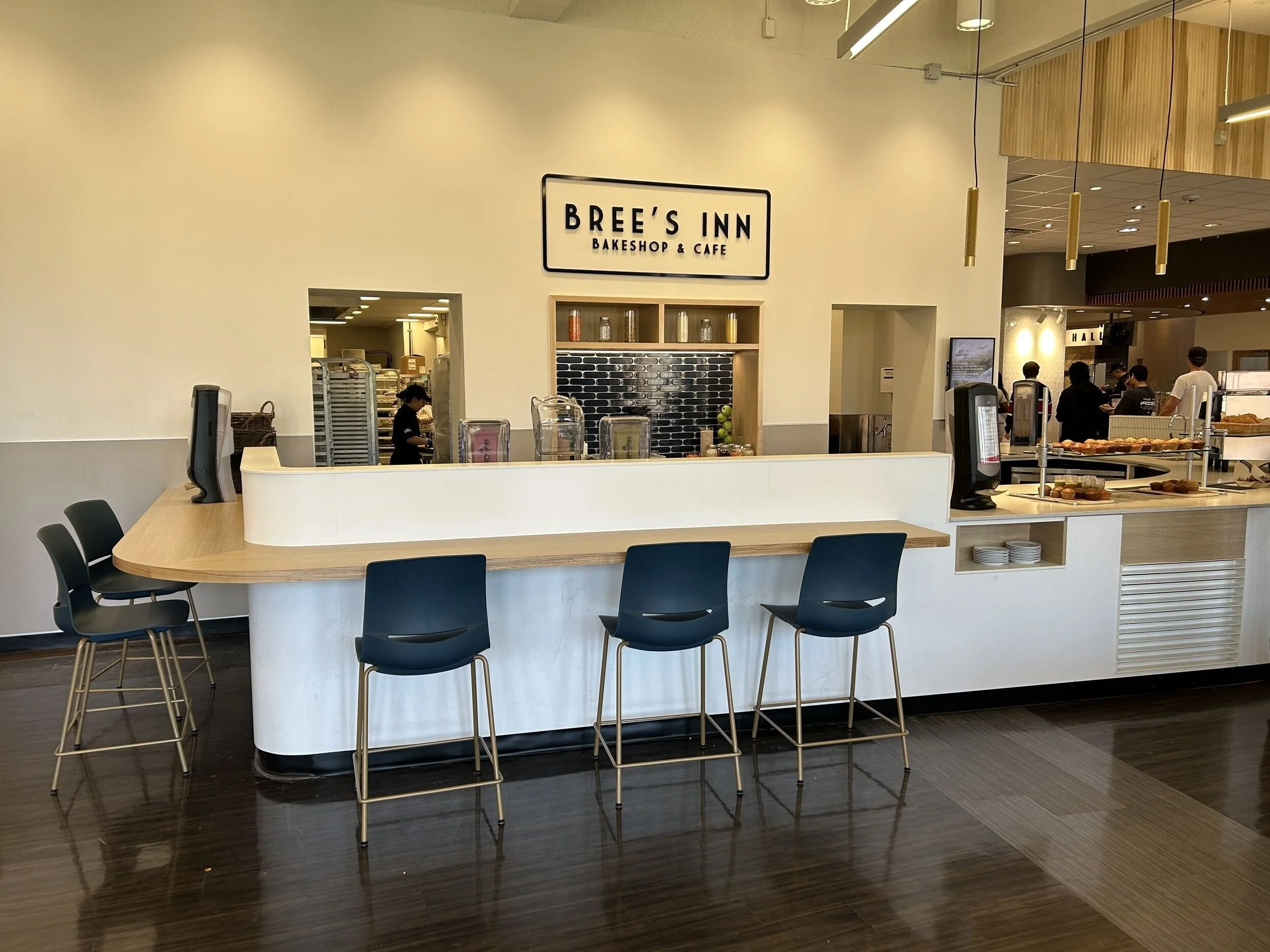 Interior of Britt's Inn Bakeshop & Cafe with a large white counter, chairs, and visible bakery items and staff behind the counter.
