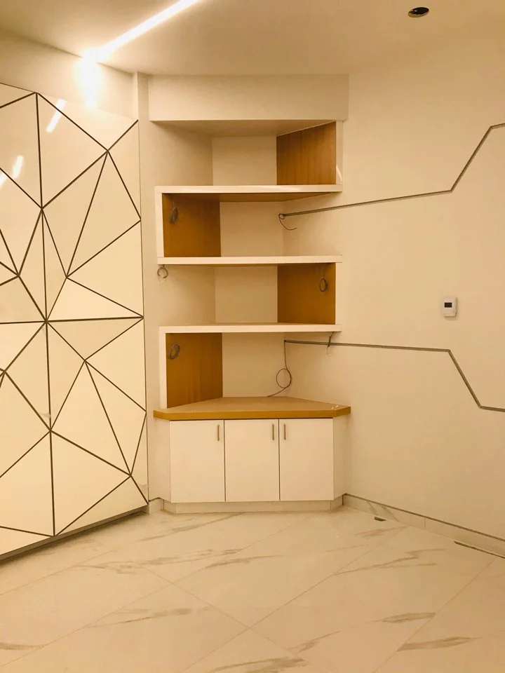 Empty built-in wall shelves with a corner cabinet below, on a modern interior wall.