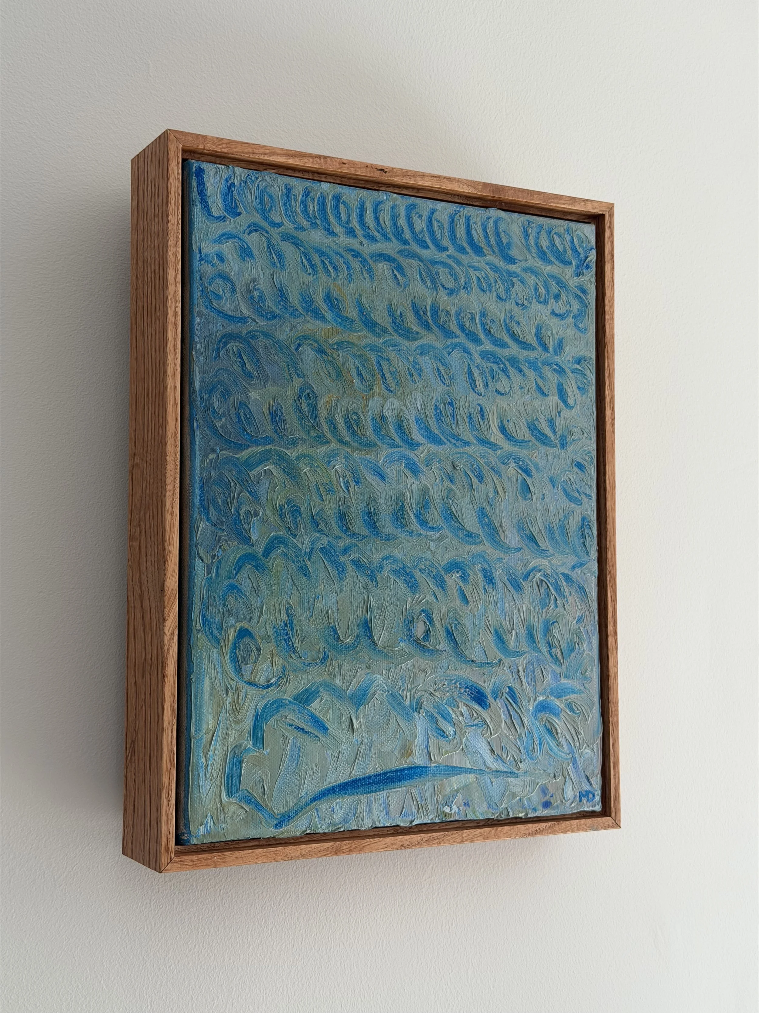 An abstract painting with swirling blue and green patterns in a wooden frame, hanging on a white wall.