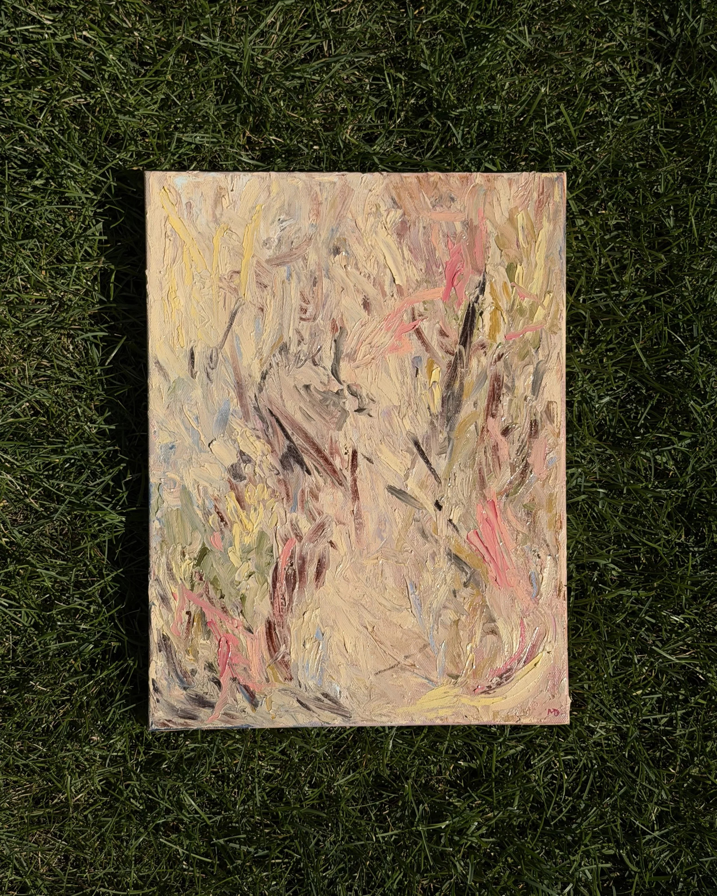 Abstract expressionist painting with pastel and earth tone colors, laid on green grass