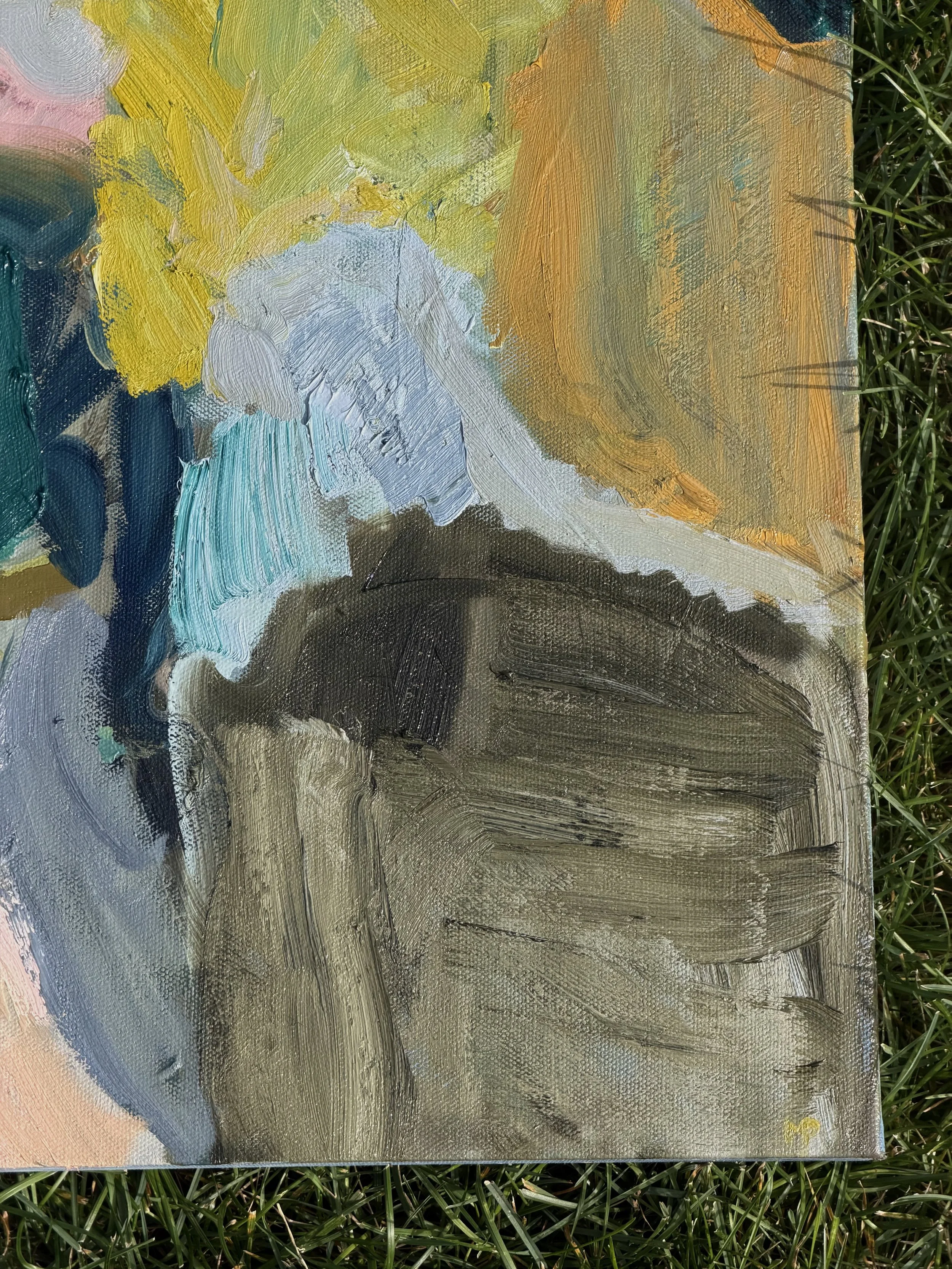 Close-up of an abstract oil painting on canvas with thick brushstrokes, featuring yellow, light blue, teal, brown, and black colors, placed on green grass.
