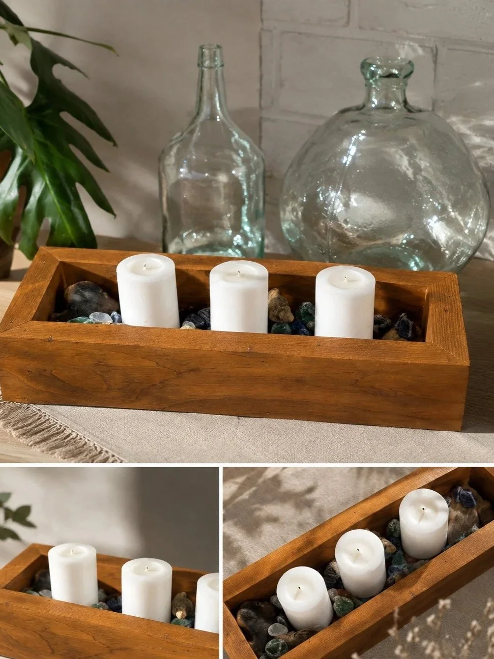 A decorative wooden tray with white candles , placed on a beige cloth with glass bottles and a potted plant in the background.