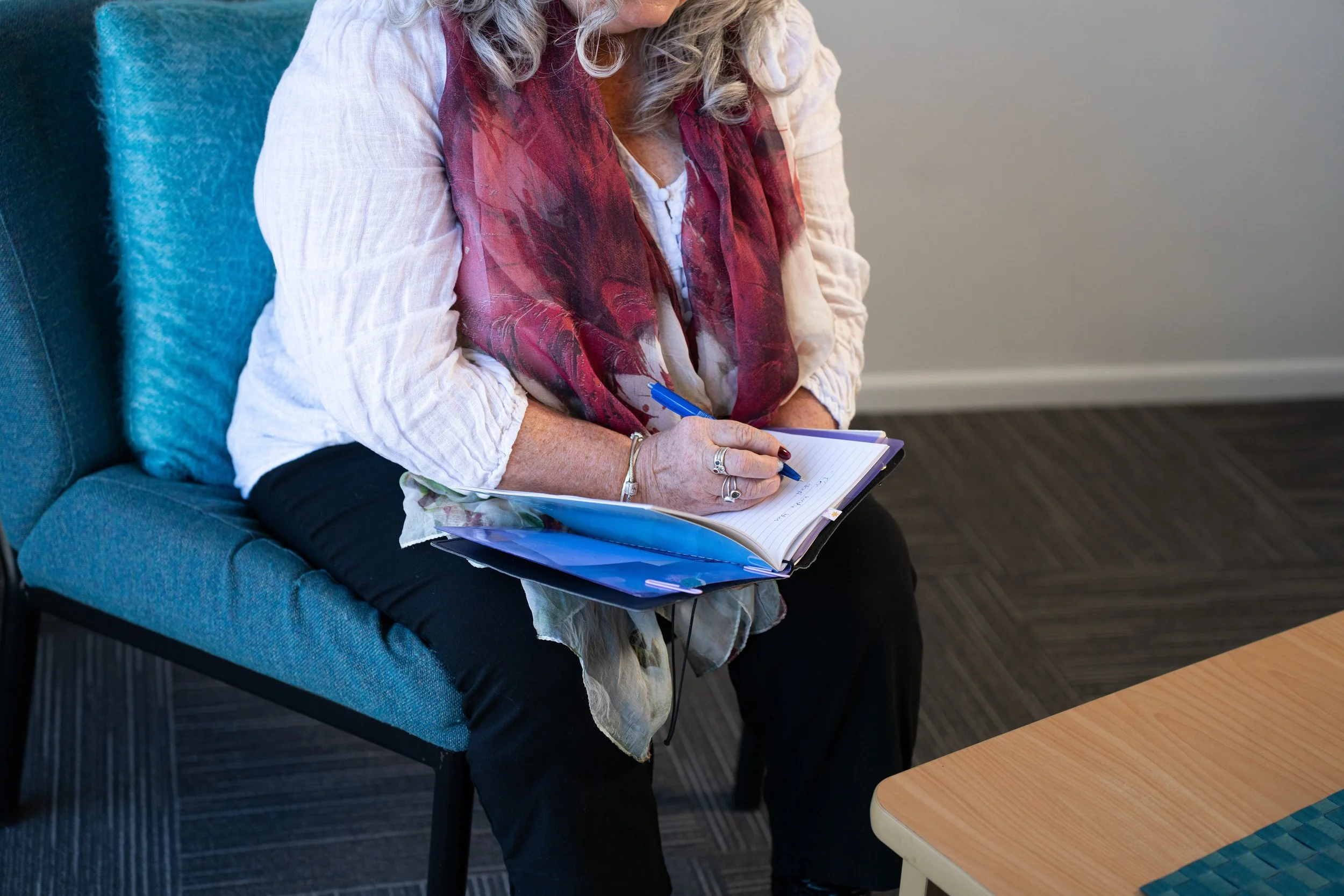 Person writing in a journal alongside supportive tools for neurodivergent individuals, representing strategies for focus, emotional regulation, self-awareness and wellbeing during counselling at Pakuranga Counselling Centre in East Auckland