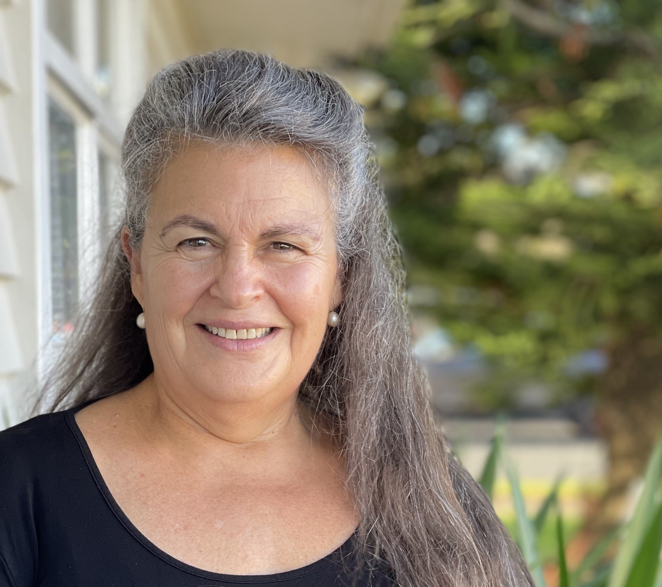 Vilma Pearson a counsellor at pakuranga counselling centre standing outdoors in front of a wall with windows wearing a black top